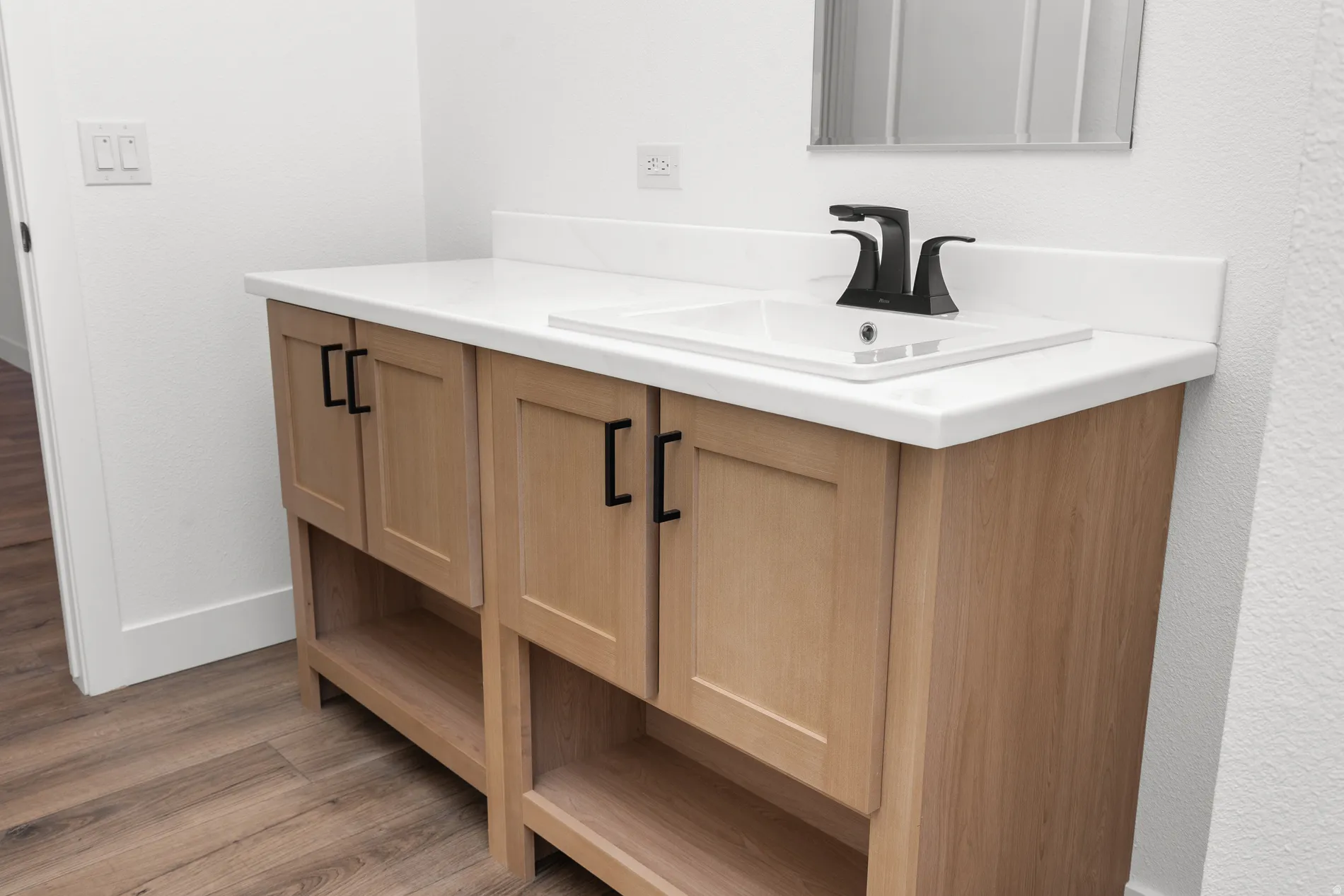 Light wood-tone vanity with a white countertop and integrated sink