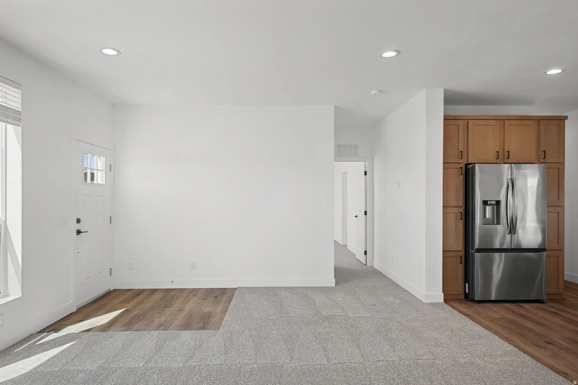 Open concept living area featuring recessed lighting and wood-finish flooring transitioning to carpet