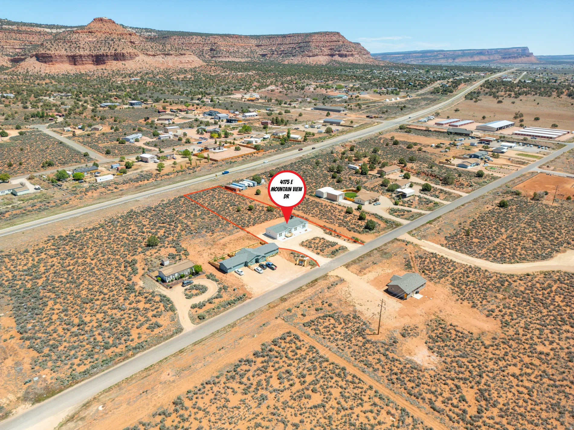 Aerial perspective featuring multiple structures on a spacious property with a backdrop of distant mesas