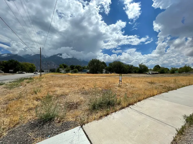 Expansive land parcel featuring a concrete sidewalk and mountain backdrop