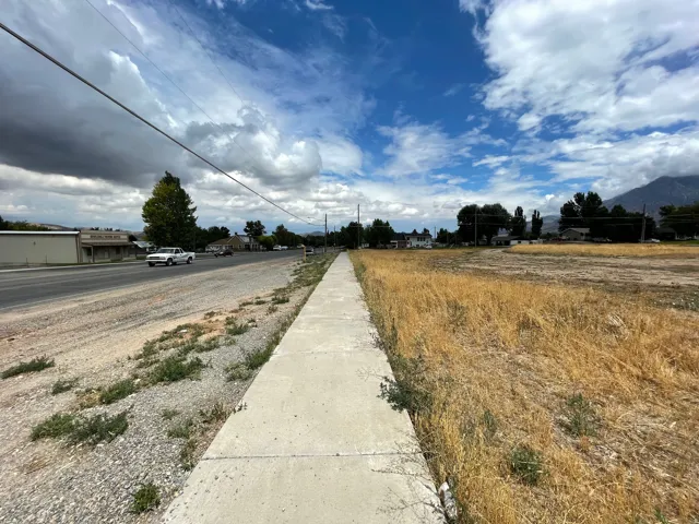 Expansive undeveloped parcel featuring a concrete sidewalk and dry vegetation