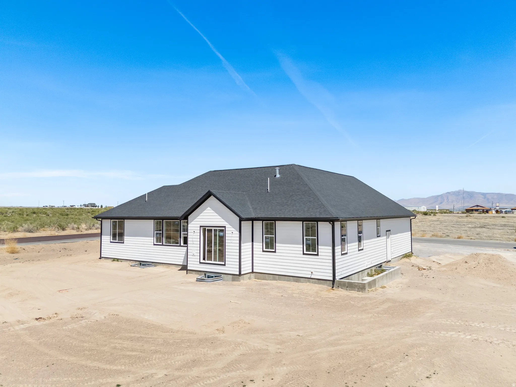 Newly constructed single-story residence featuring white horizontal siding and a dark shingle roof