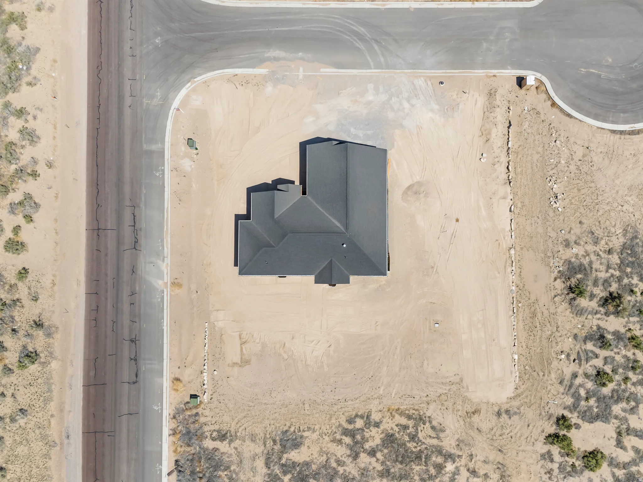 Property featuring a dark shingle roof, a corner lot position, and undeveloped surrounding land