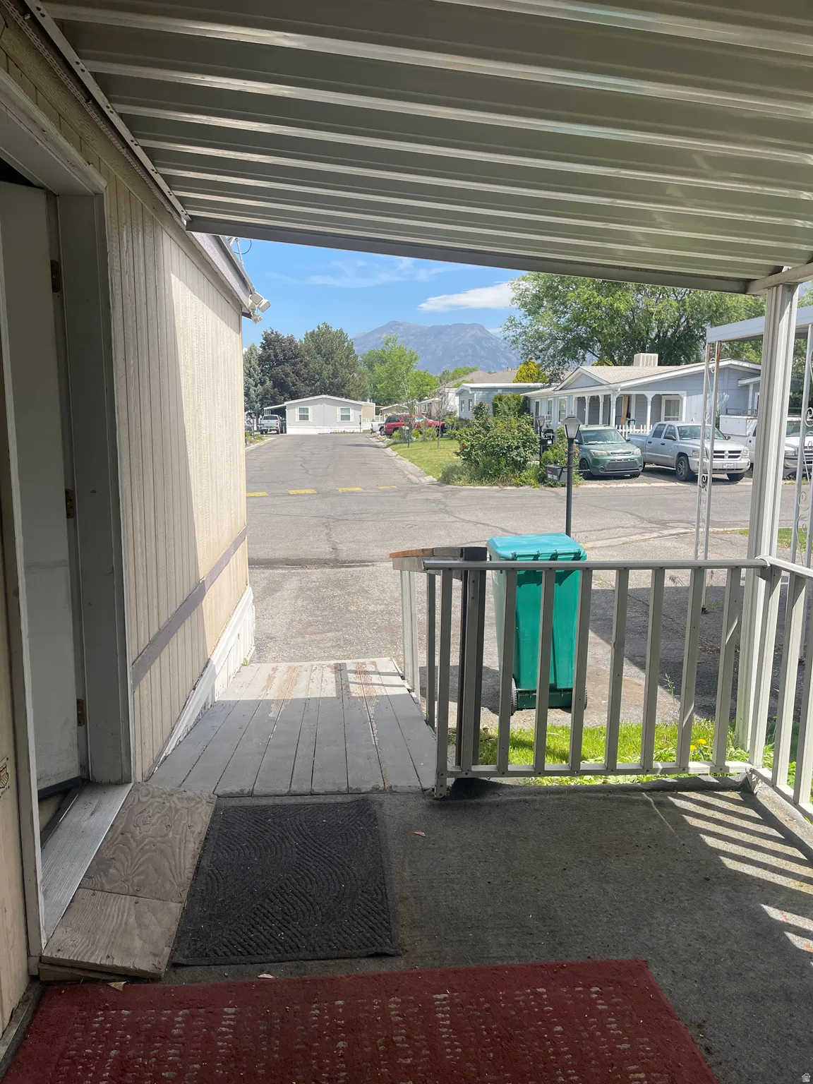 Covered porch entrance with metal railings, offering a distant mountain backdrop