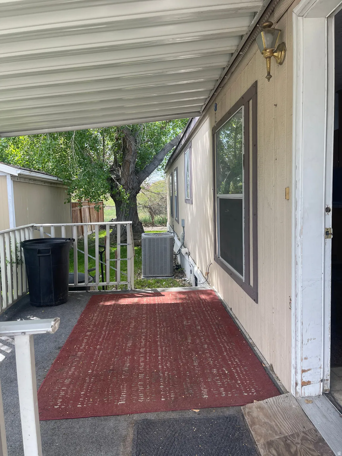 Covered exterior patio featuring a metal awning and outdoor lighting fixture