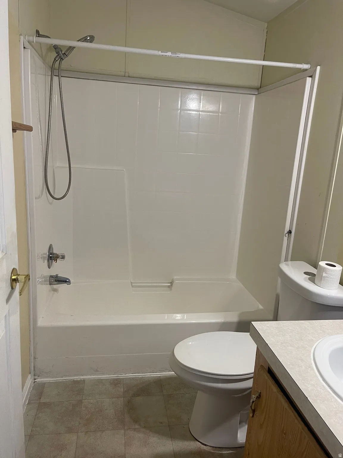 White bathtub with integrated shower, chrome fixtures, and a handheld showerhead