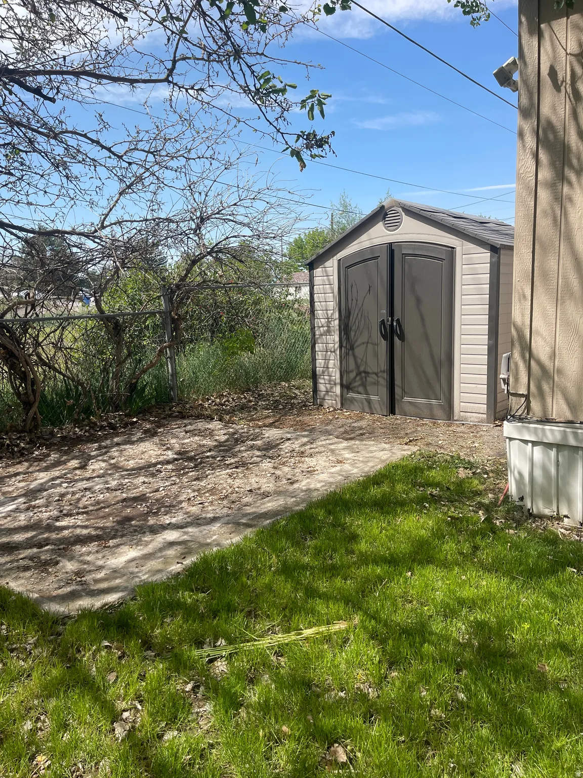 Compact storage shed with a neutral-toned exterior, double doors, and roof vent, situated on a stone-finish pad