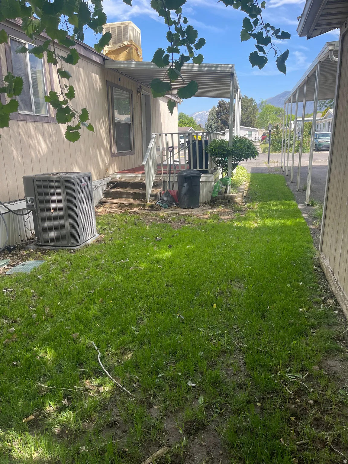 Side yard with green grass, leading to a covered entrance and a windowed exterior wall