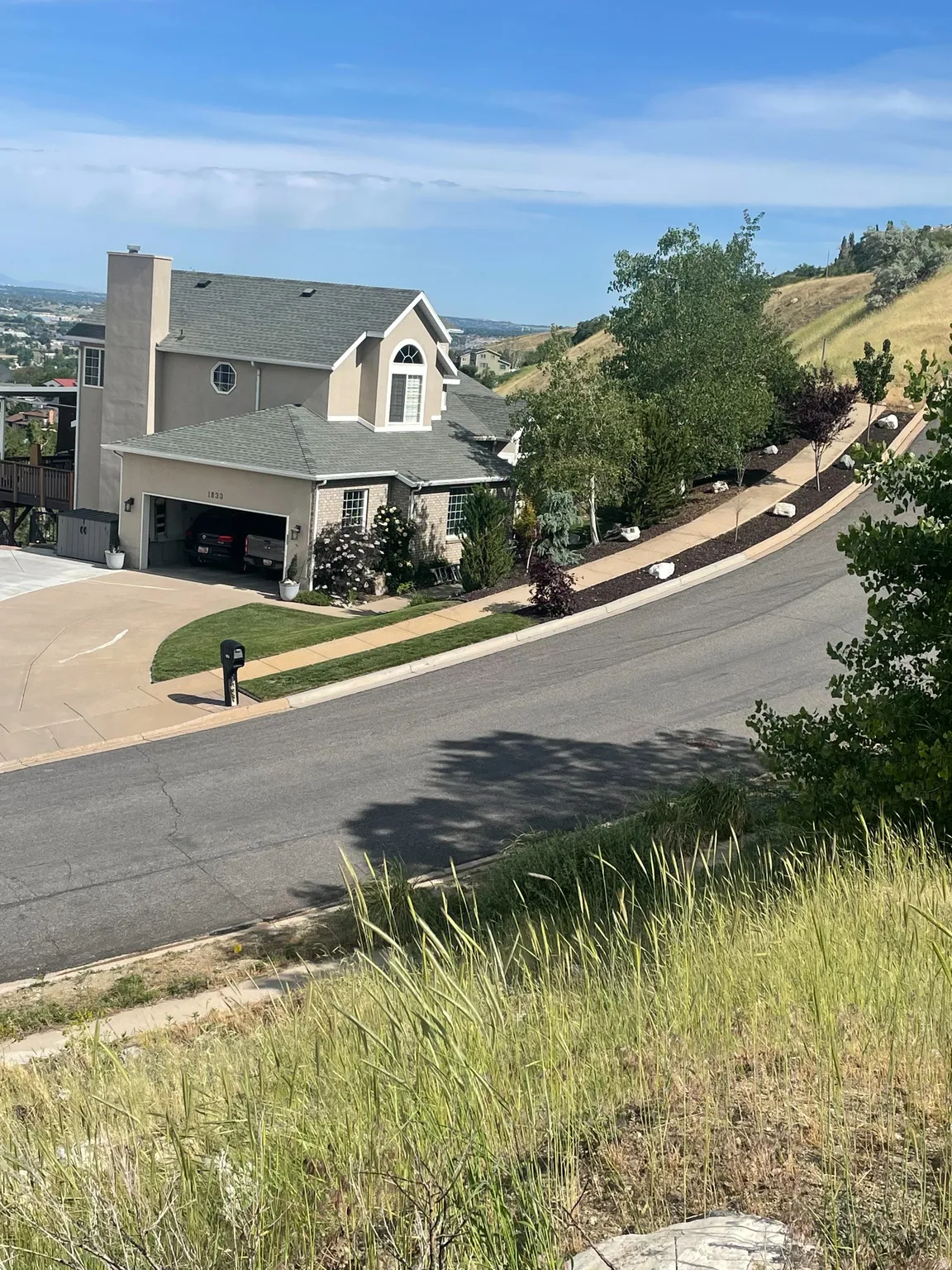 Sloped property featuring a light beige exterior, a prominent chimney, and a two-car garage