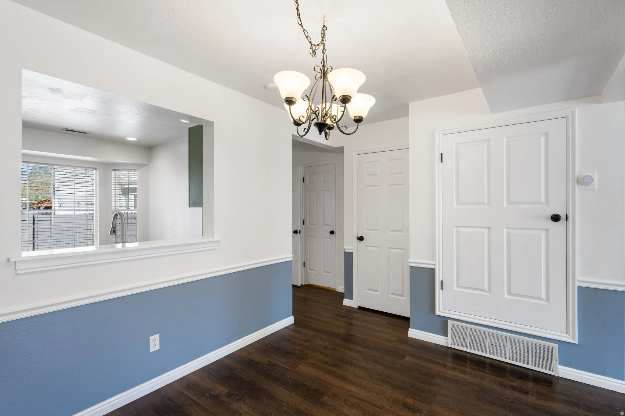 Dining area featuring wood-finish flooring, white and blue wall paneling, and a four-light chandelier
