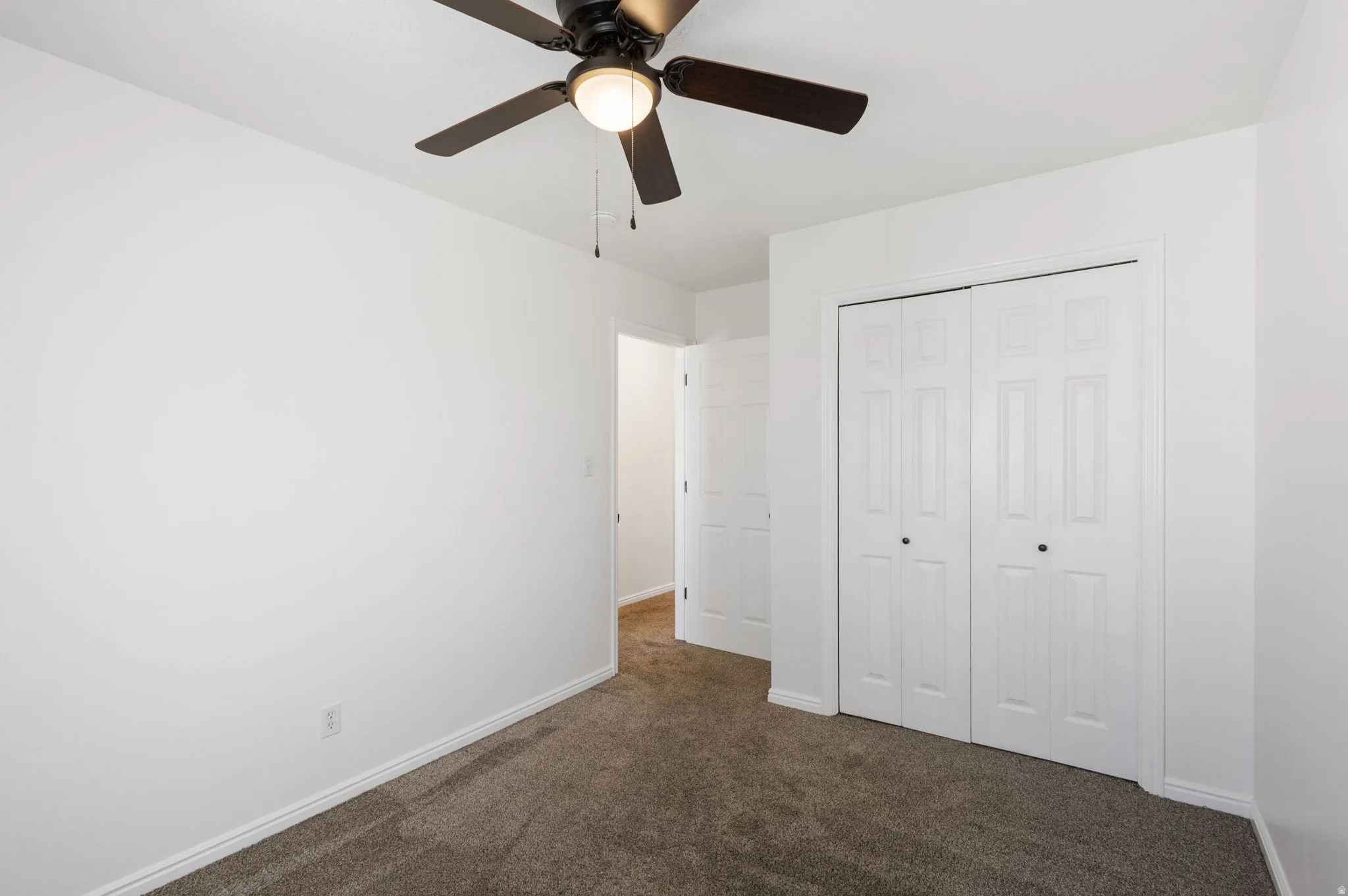 Room featuring neutral carpet flooring, white walls, and a ceiling fan with integrated lighting