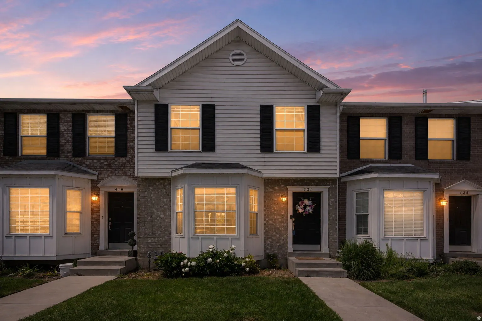 Two-story townhome featuring a mixed facade of siding and brick, accented by bay windows and black louvered shutters