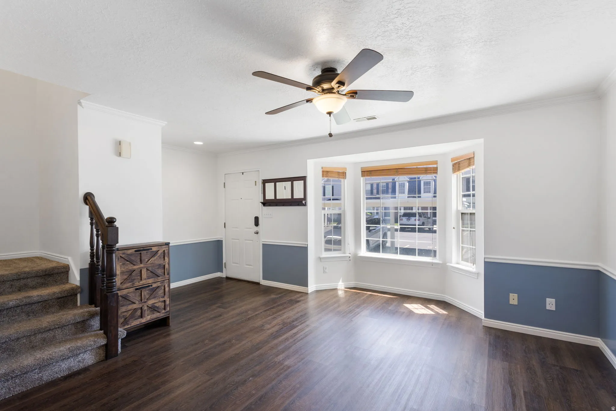 Expansive living area featuring wood-finish flooring and a bay window with natural light