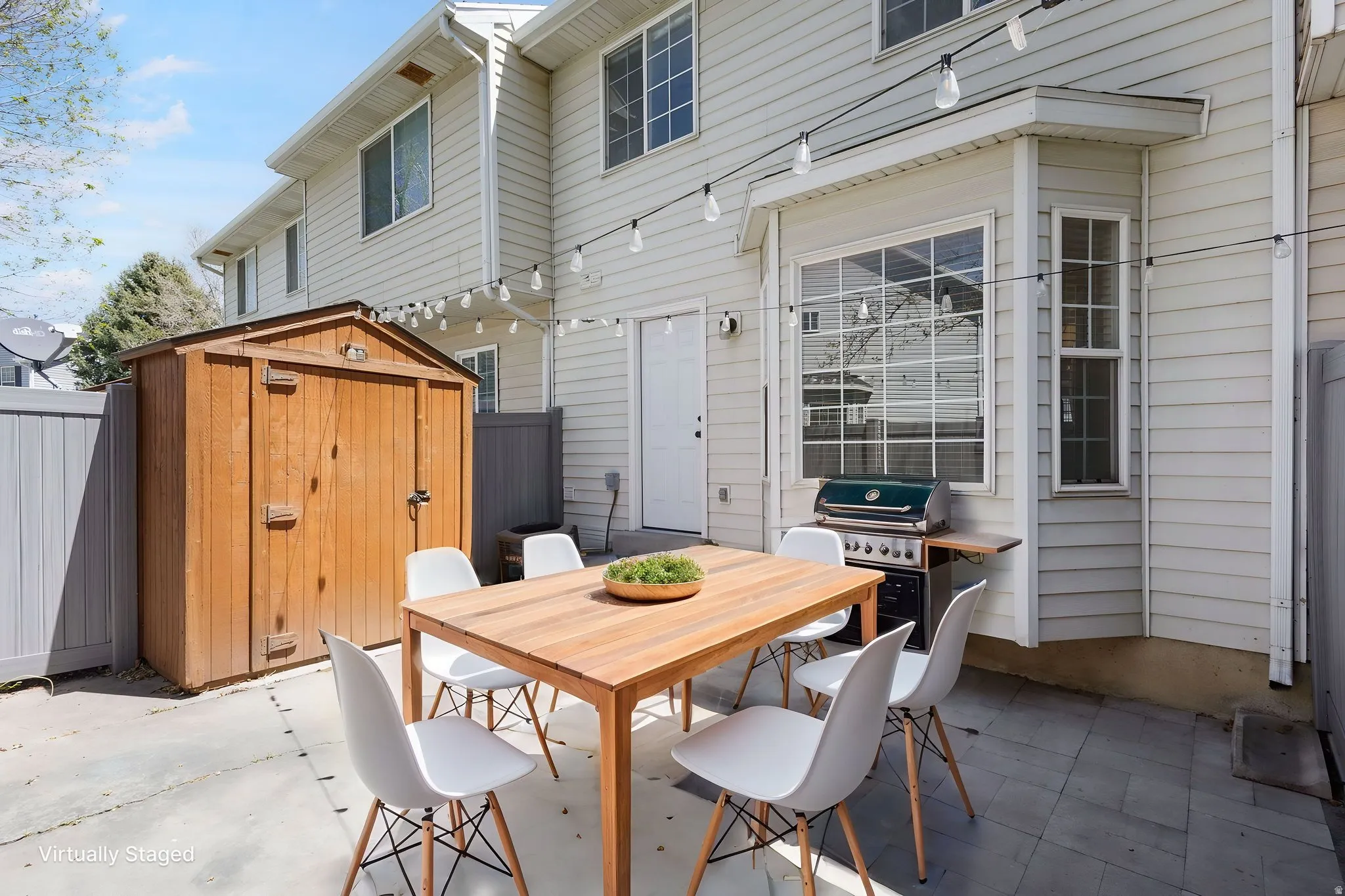 Paved Patio (Virtually staged photo) Paved patio area featuring string lighting and a built-in outdoor grill