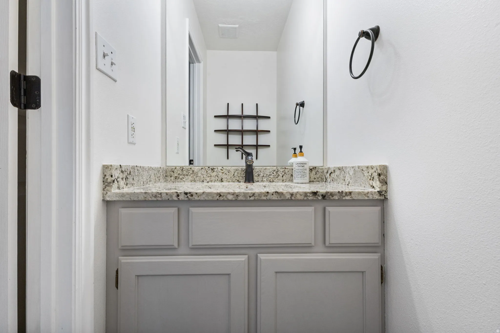 Bathroom vanity with a speckled countertop, undermount sink, and matte black faucet