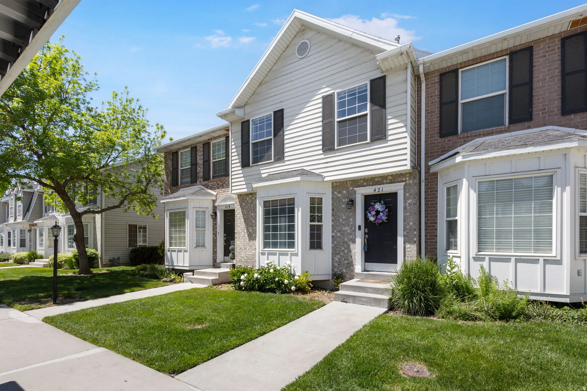 Front exterior featuring white siding, brick accents, and a dark entry door