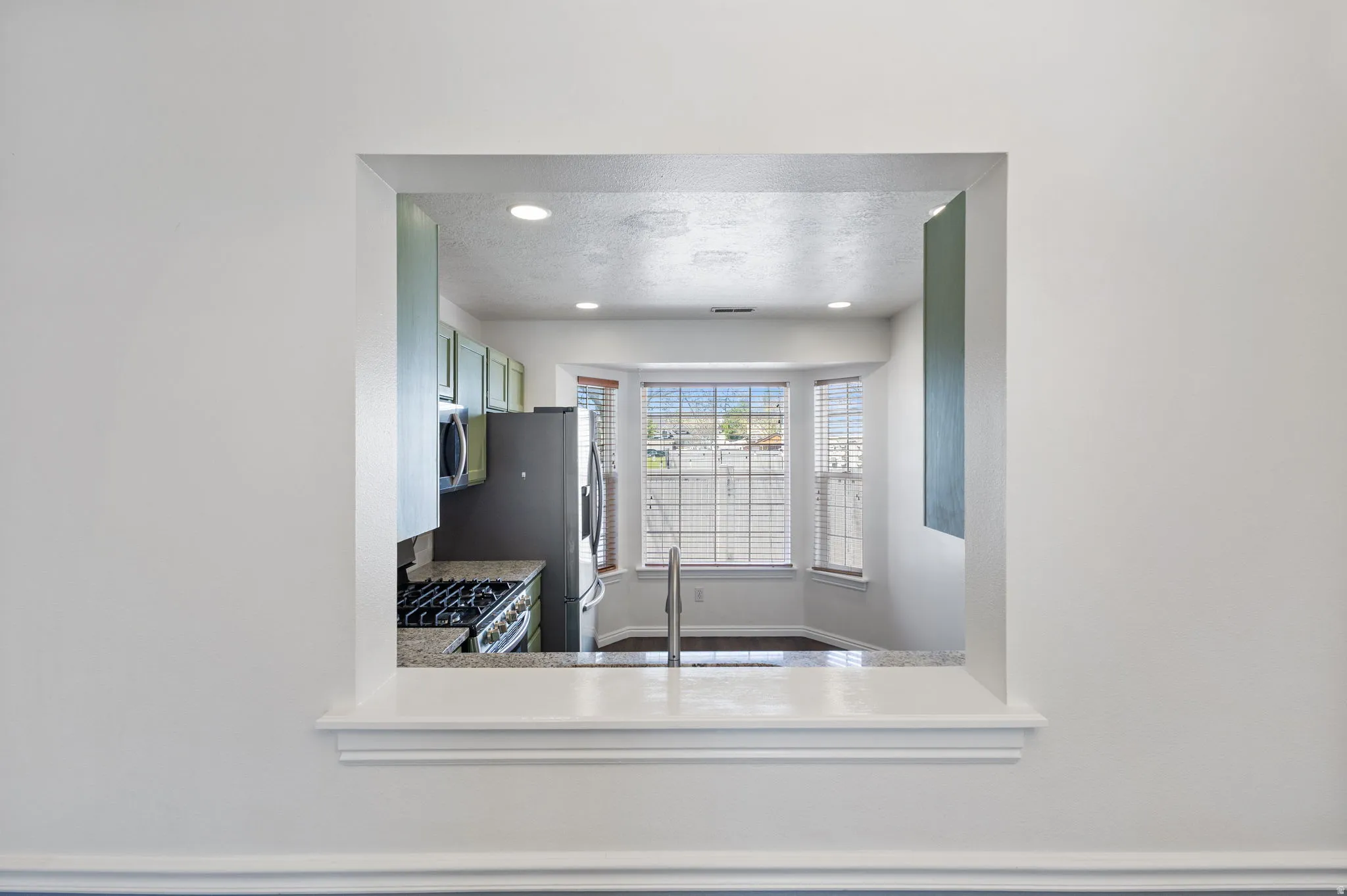 Kitchen pass-through featuring a granite-style countertop and a gas range