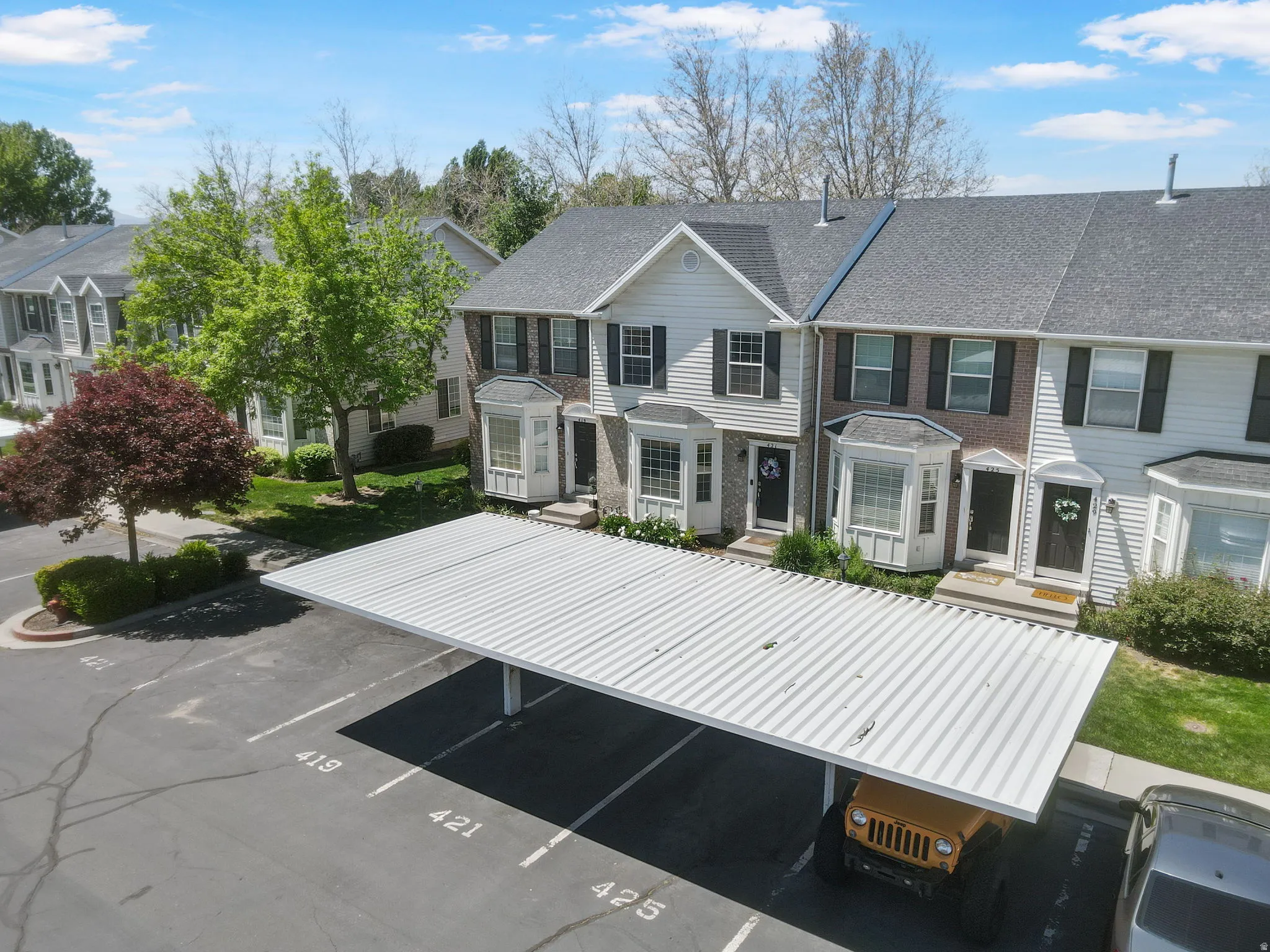Carport structure offering covered parking. 2 labeled parking spaces one covered and uncovered