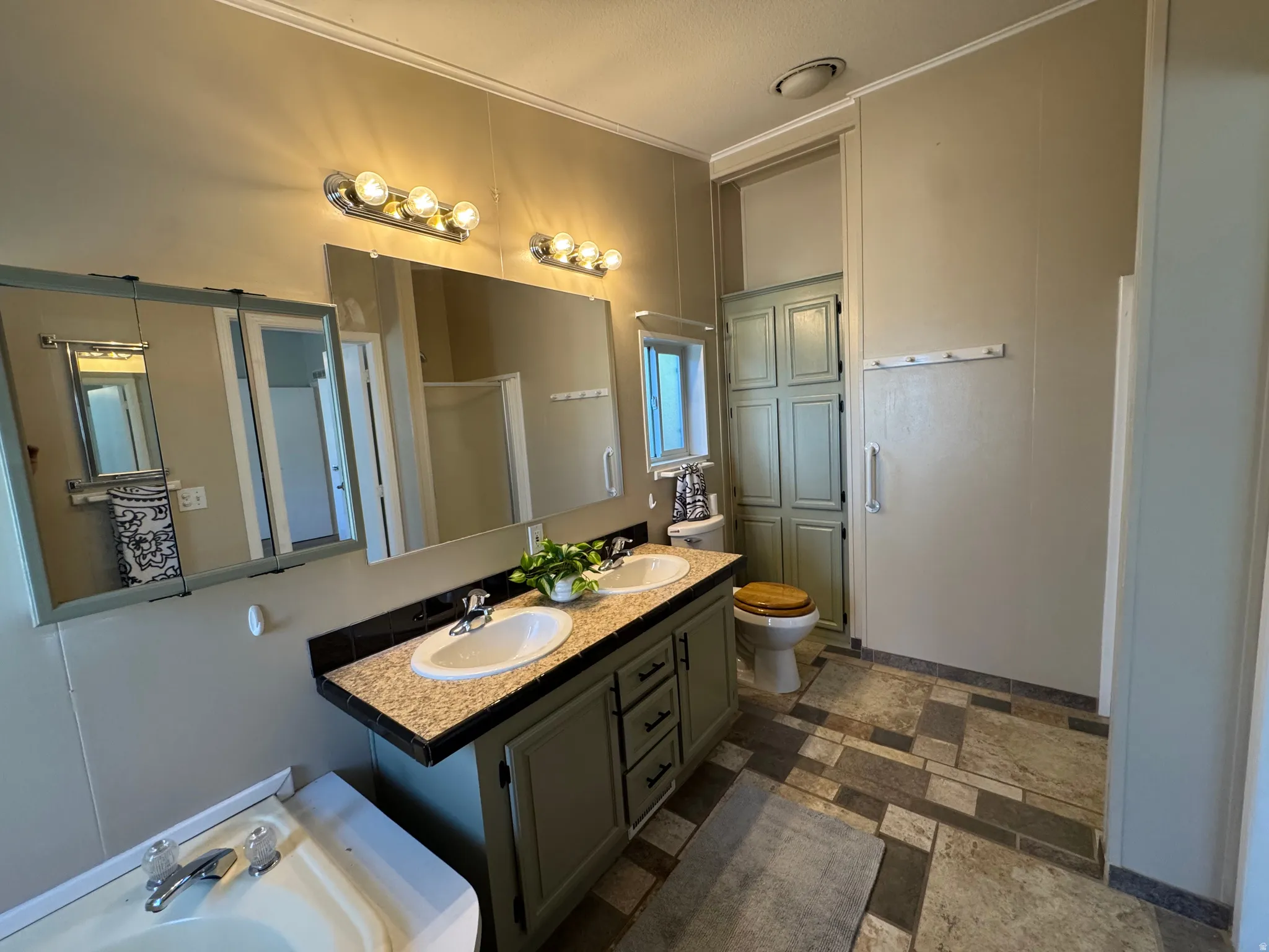 Bathroom featuring a double vanity with stone-finish countertops, dual sinks, and built-in cabinetry