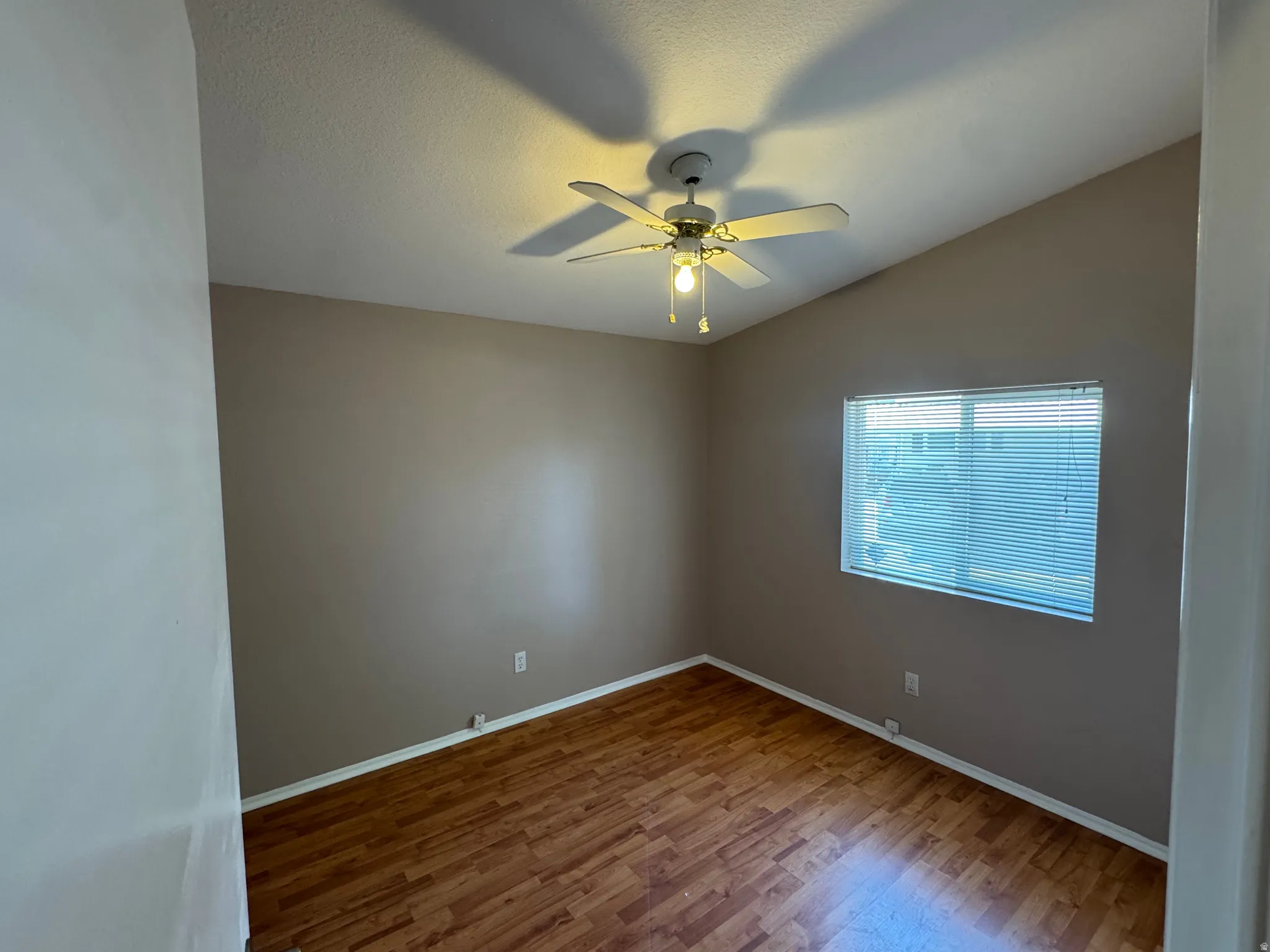 Interior room featuring wood-finish flooring, a vaulted ceiling, and a ceiling fan with integrated lighting