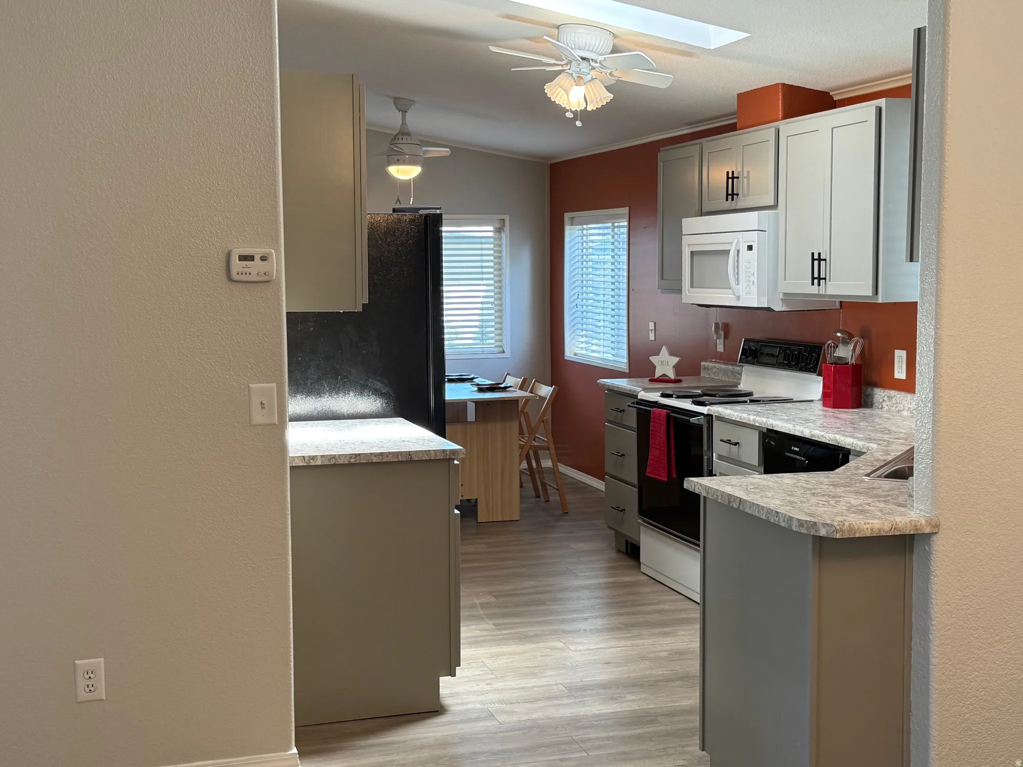 Kitchen featuring wood-finish flooring, light grey cabinetry with dark hardware, and speckled countertops