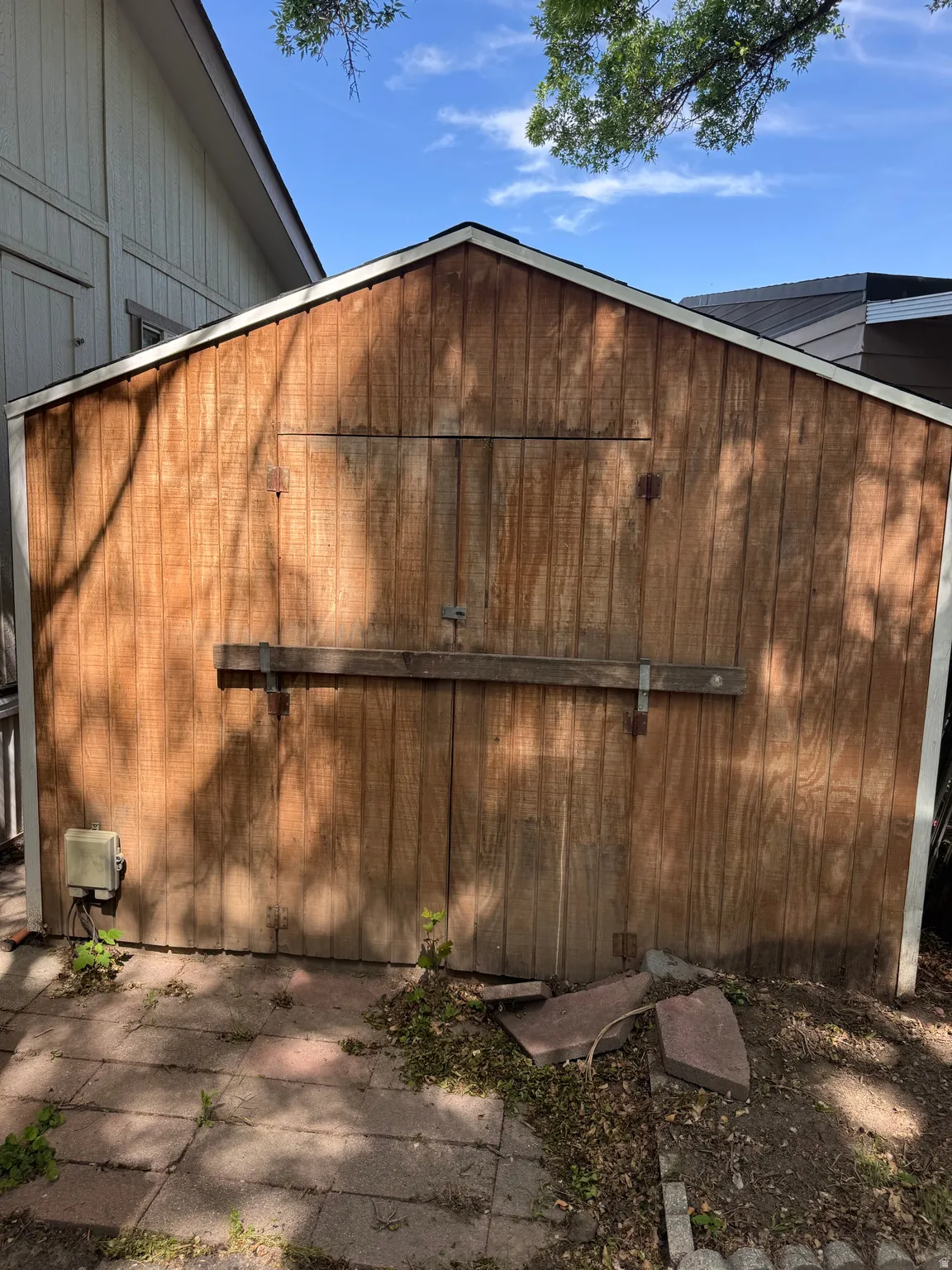 Wood-sided shed featuring a gabled roof and integrated double doors