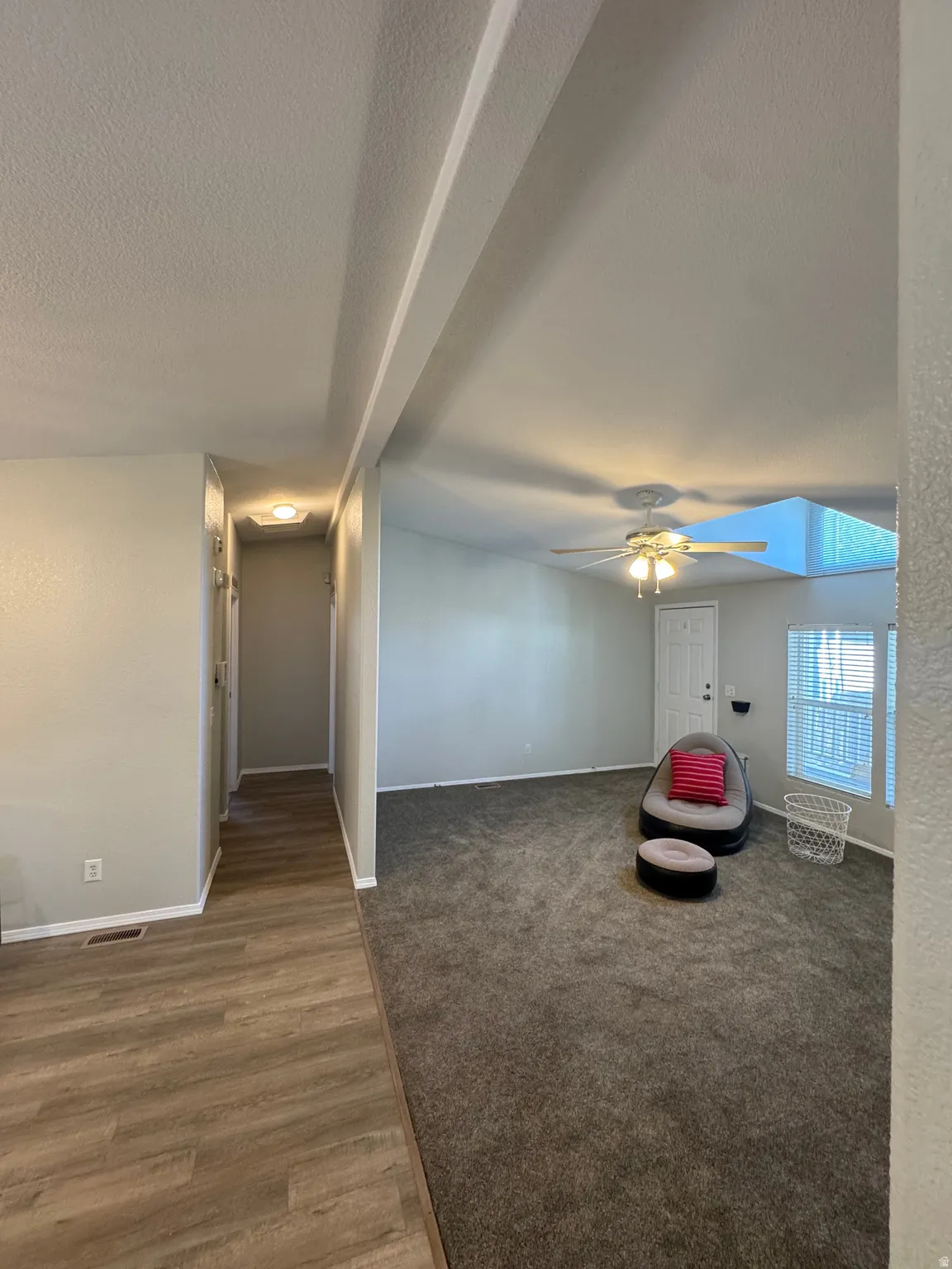 Open-concept living area featuring a ceiling fan, light gray wall finishes, and a white door