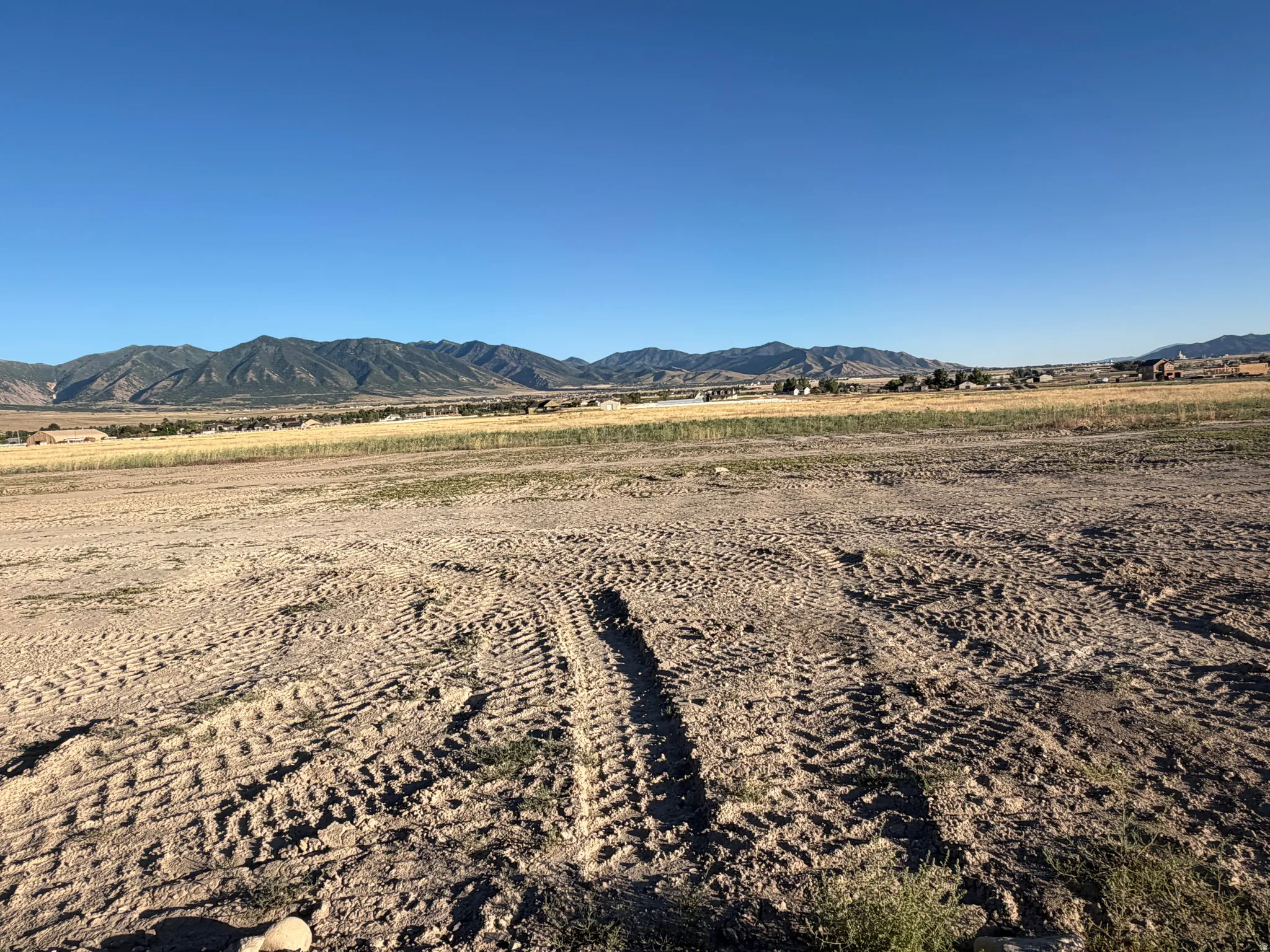 Expansive cleared lot featuring mountain scenery and distant structures