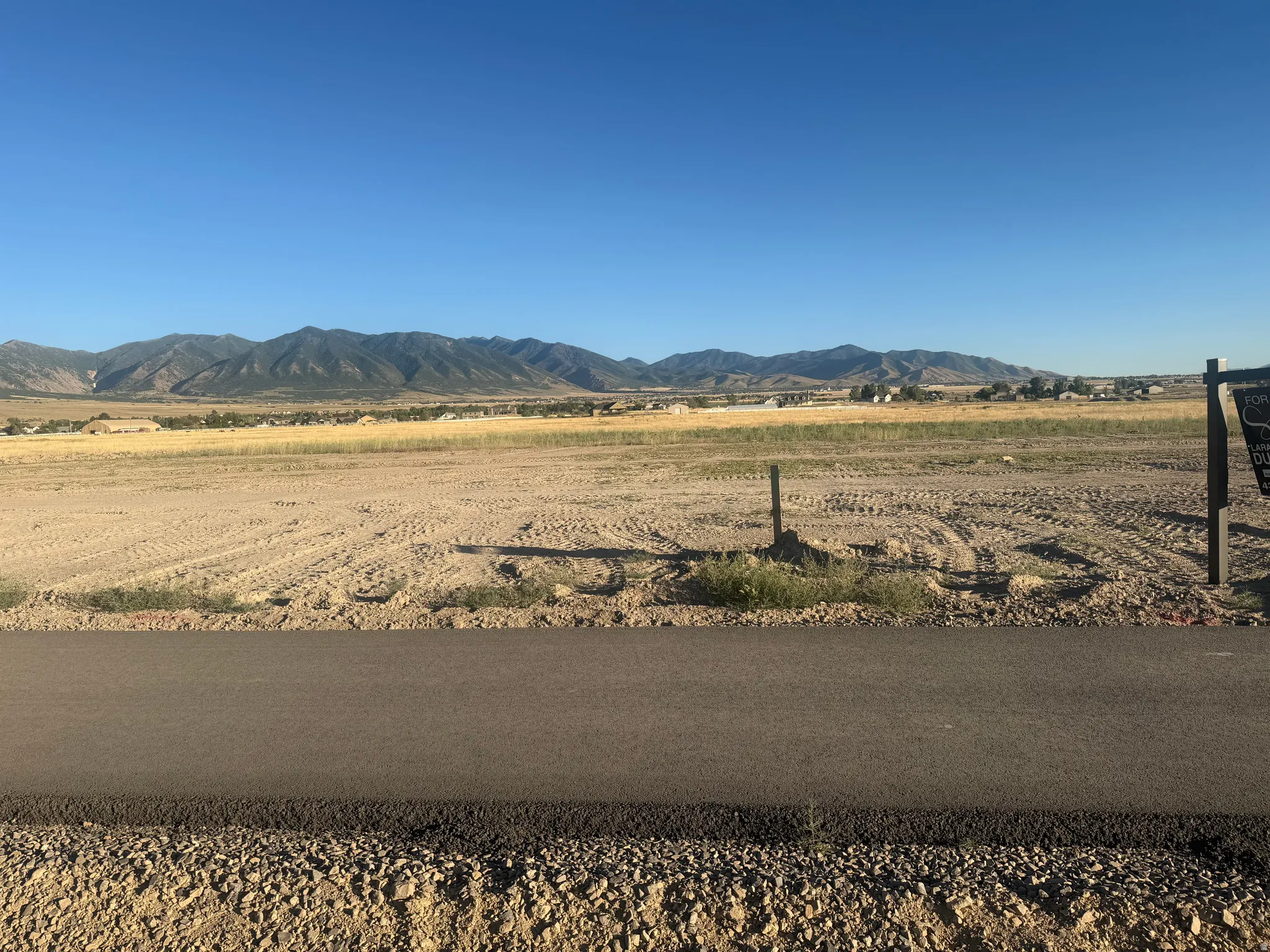 Expansive undeveloped land featuring a paved road frontage and distant mountain range