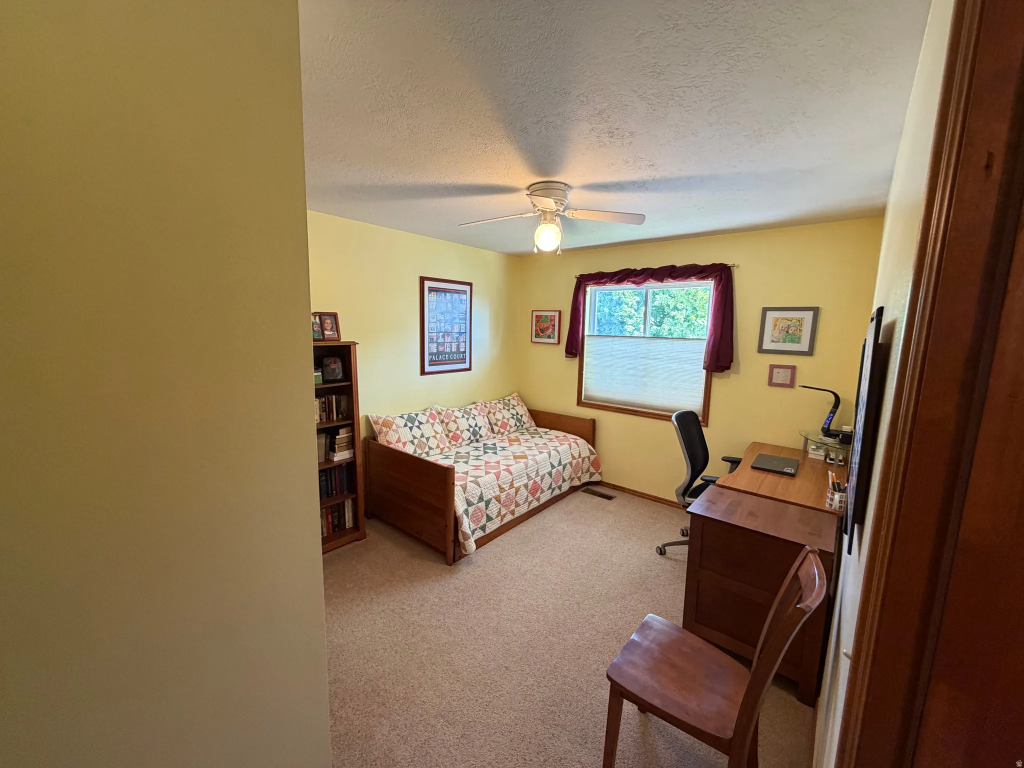 Carpeted interior room with a ceiling fan, a window, and wood-finish trim