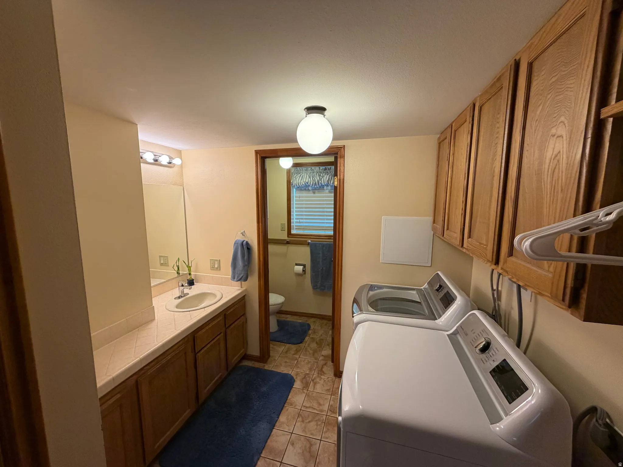 Integrated laundry area featuring wood-finish cabinetry, a top-load washing machine, and a front-load dryer