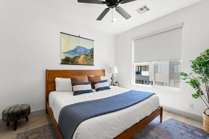 Bright room featuring a ceiling fan, light wood-finish flooring, and a large window with a roller shade