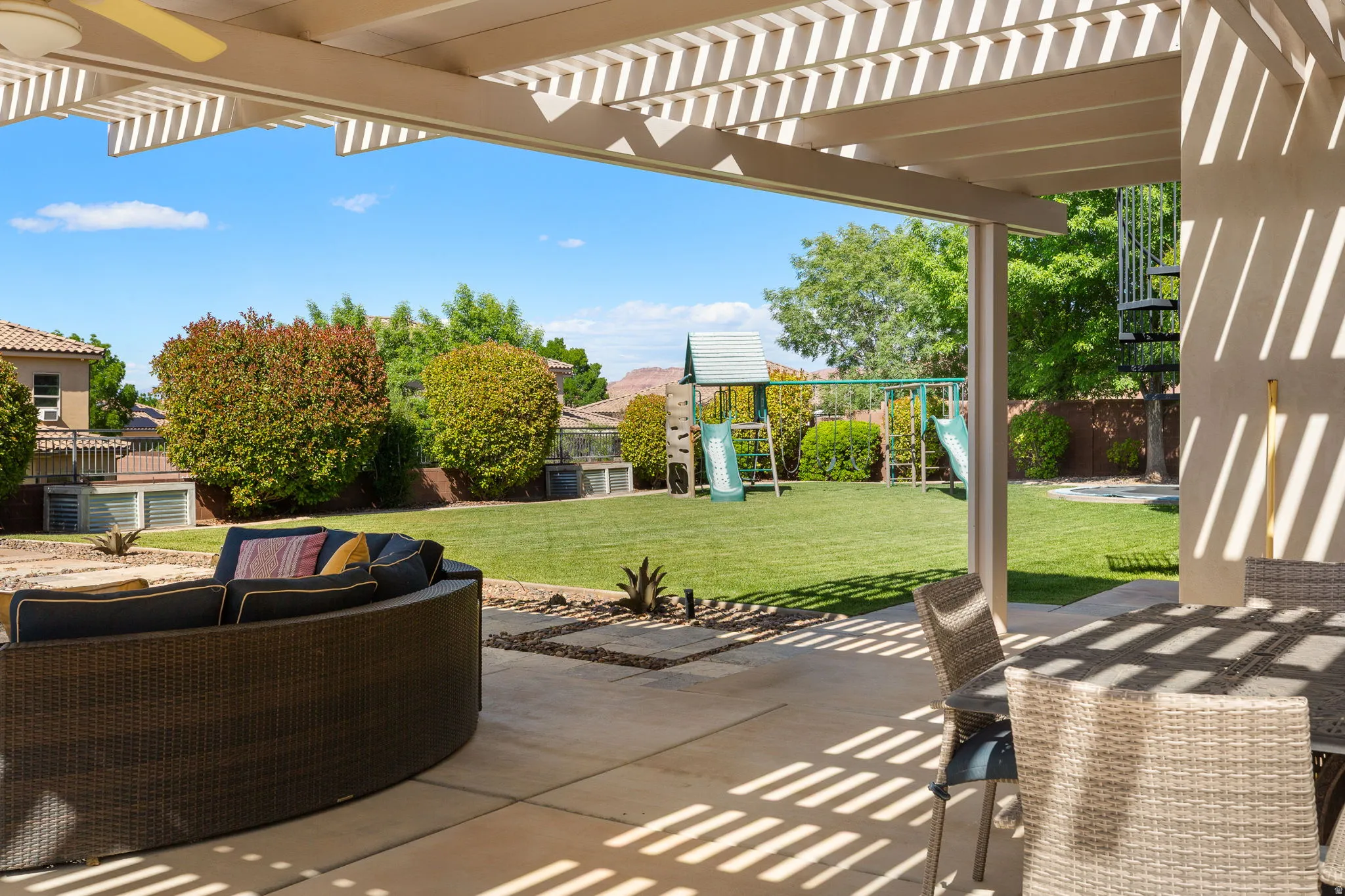 Spacious outdoor patio with a full-length pergola, concrete flooring, and an expansive lawn