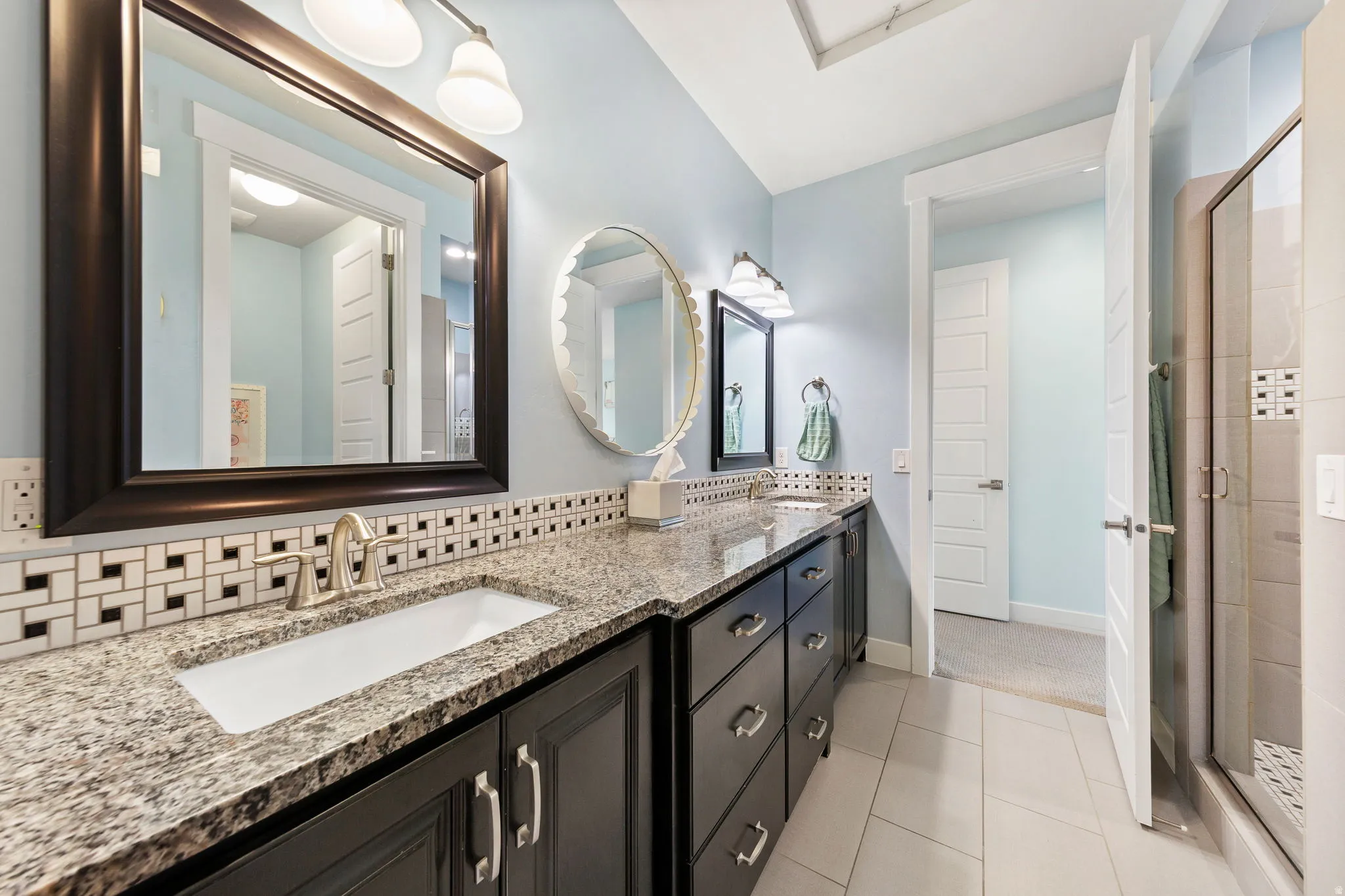 Double vanity featuring granite countertops, undermount sinks, and dark wood-finish cabinetry