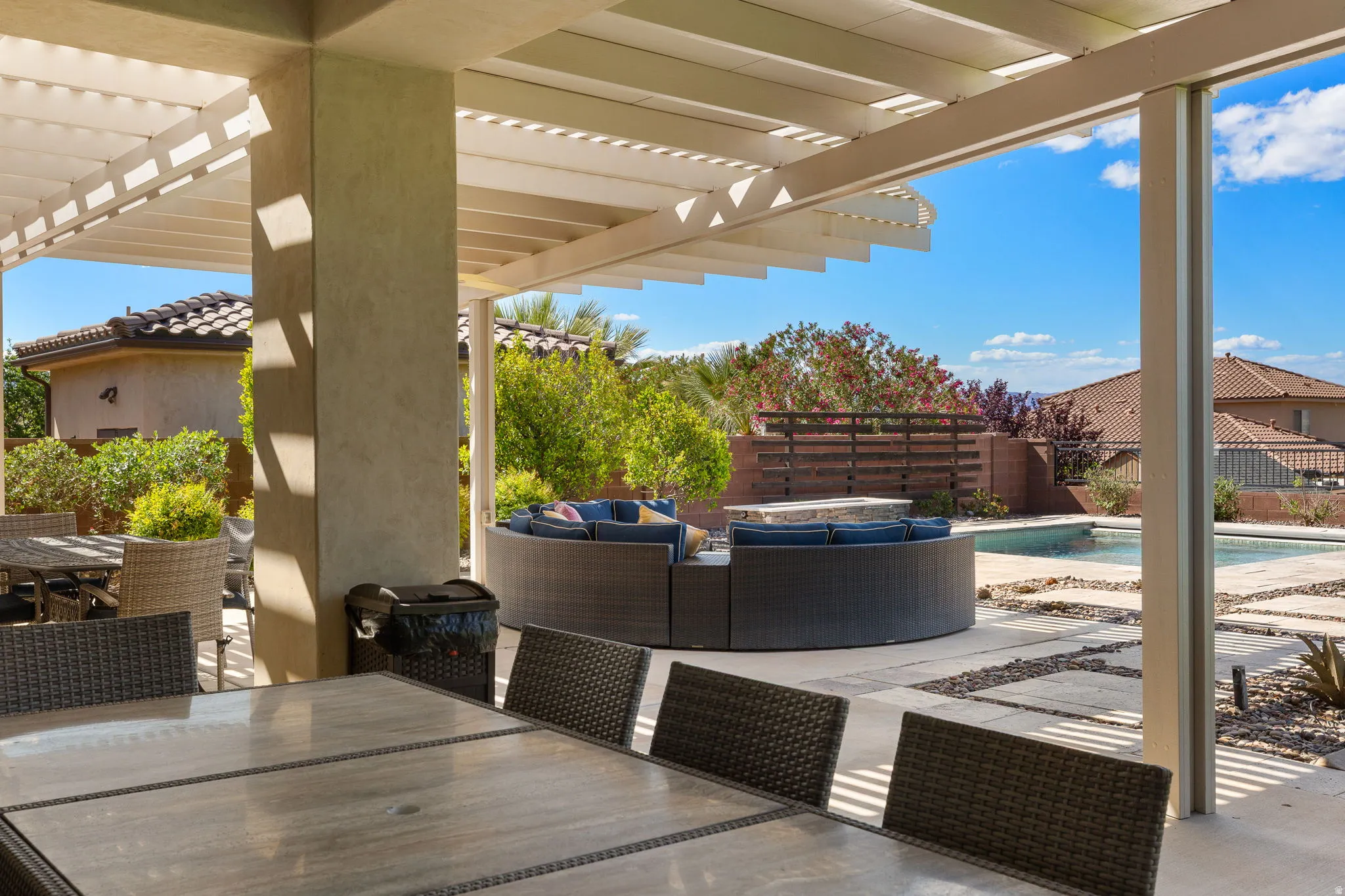 Expansive covered patio featuring a slatted pergola roof and concrete pillars