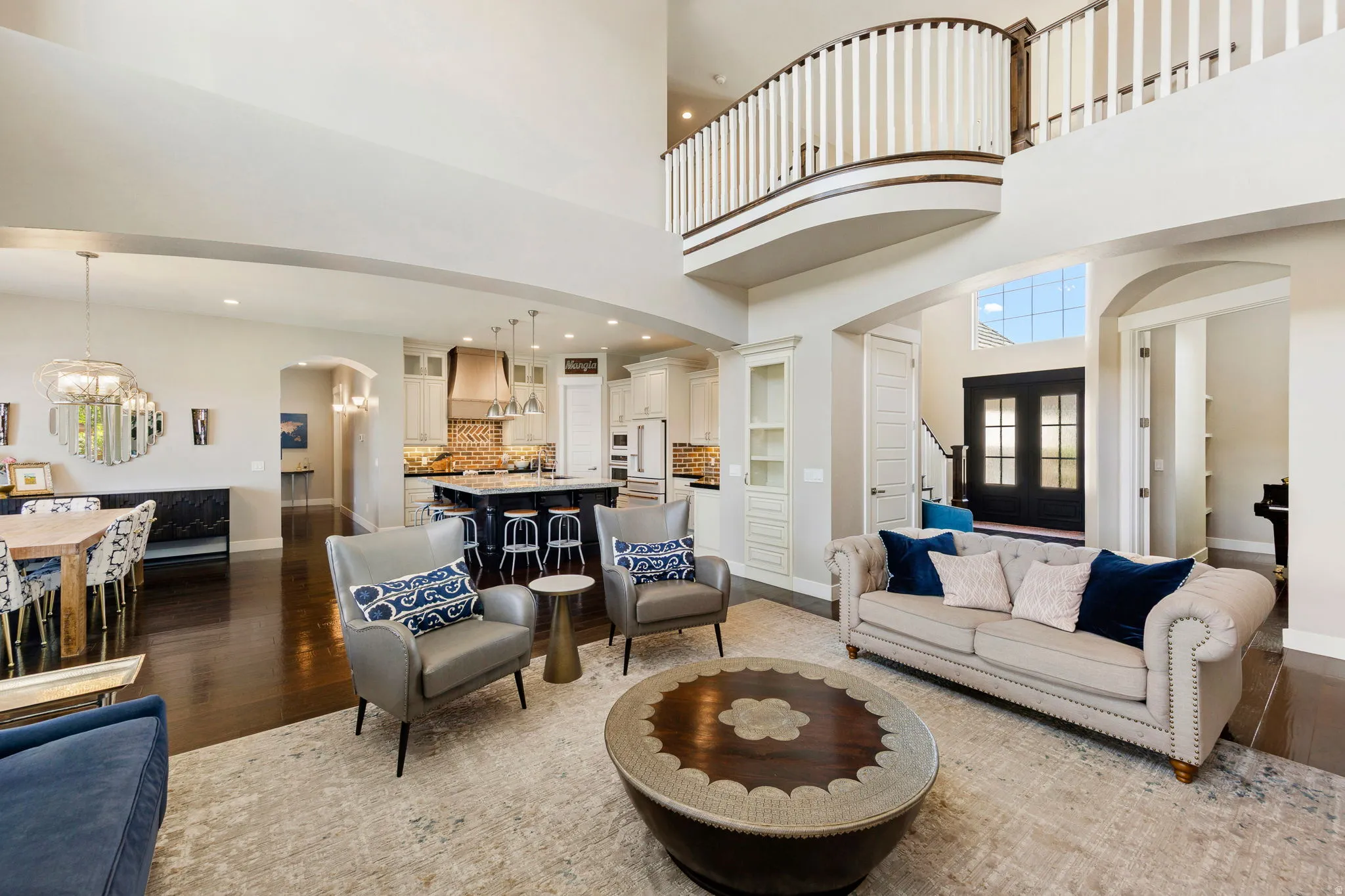 Open-concept living area with dark wood-finish flooring, a two-story ceiling, and an upper-level balcony