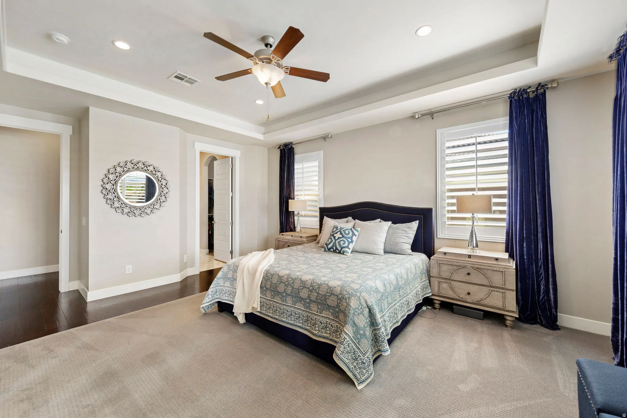 Carpeted bedroom featuring a tray ceiling with recessed lighting and a ceiling fan