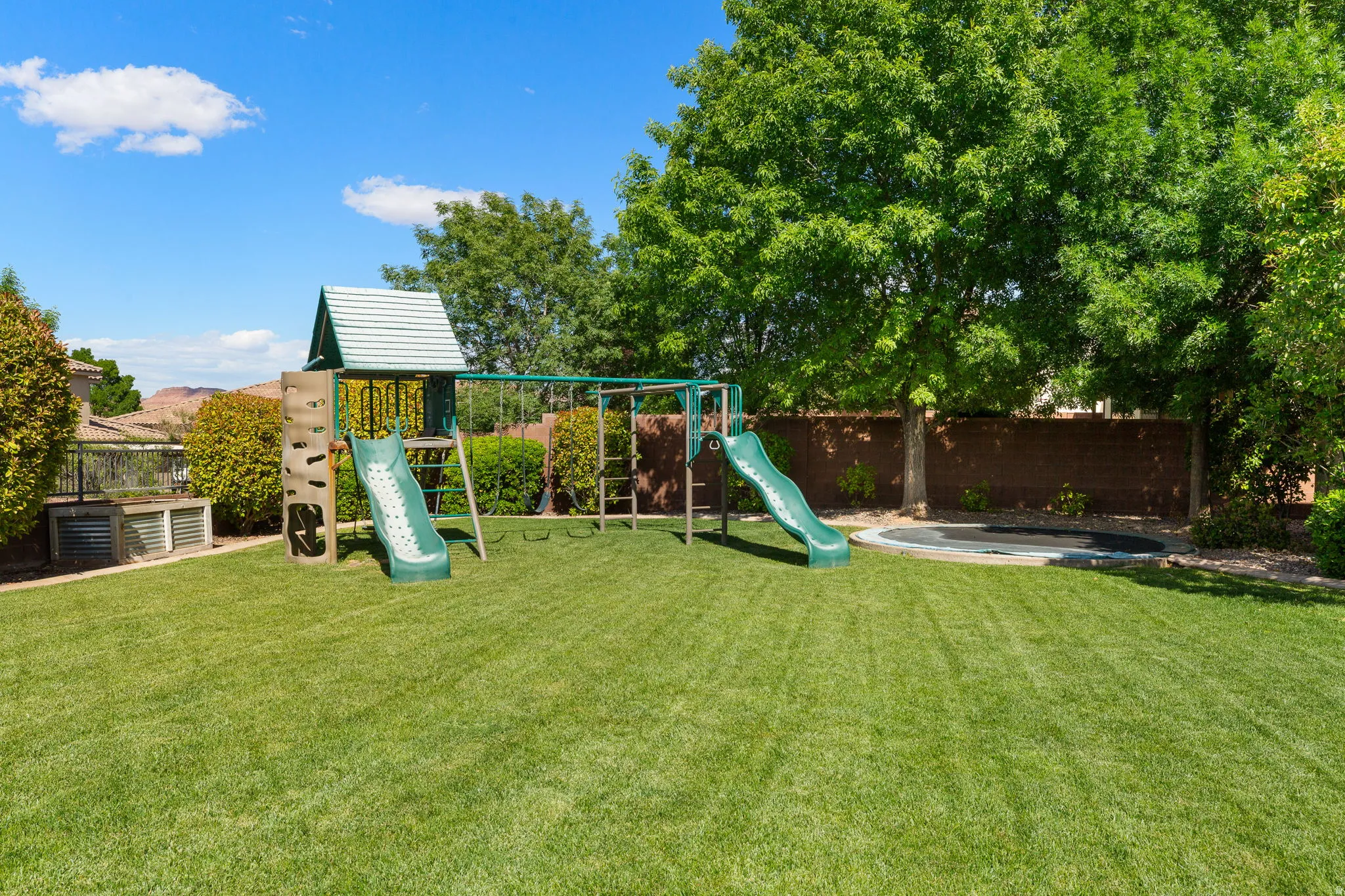 Expansive backyard featuring a lush green lawn, mature trees, and a privacy fence