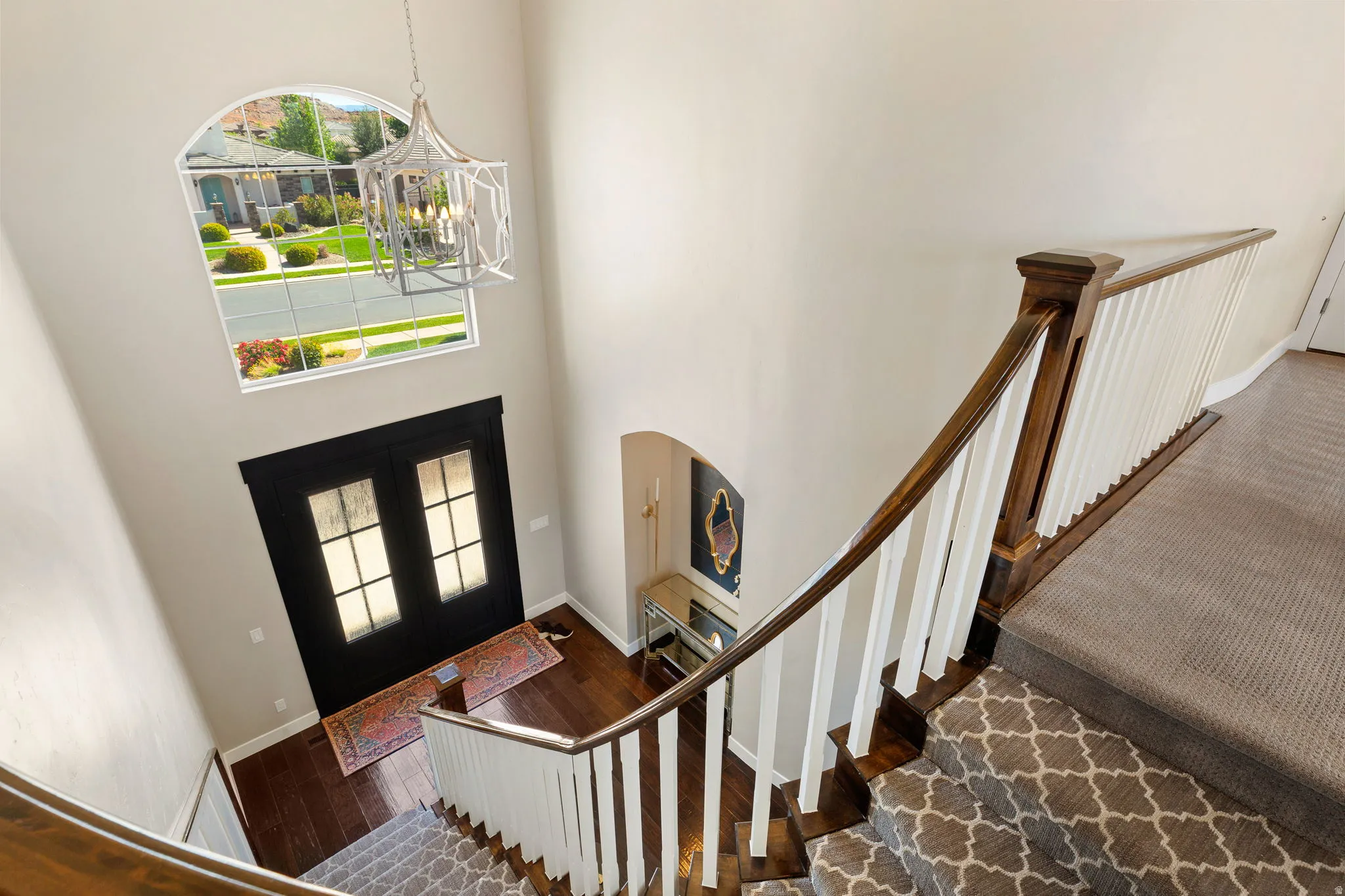 Two-story entryway featuring a dark wood-finish double entry door with frosted glass panes