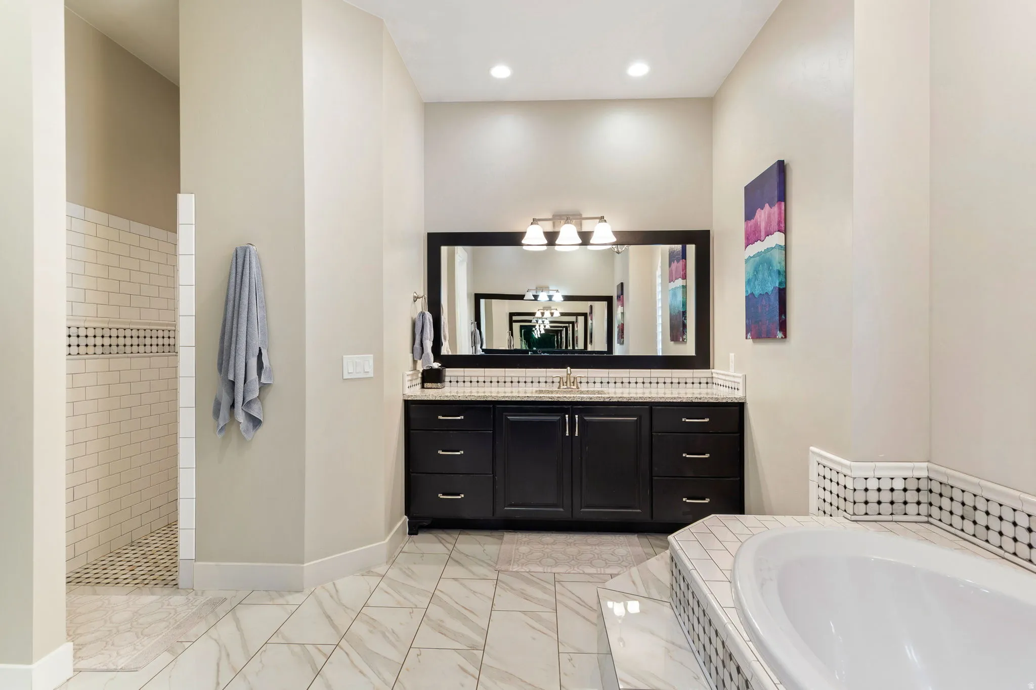 Spacious bathroom featuring a dark wood vanity with a light-colored countertop, an undermount sink, and an expansive framed mirror