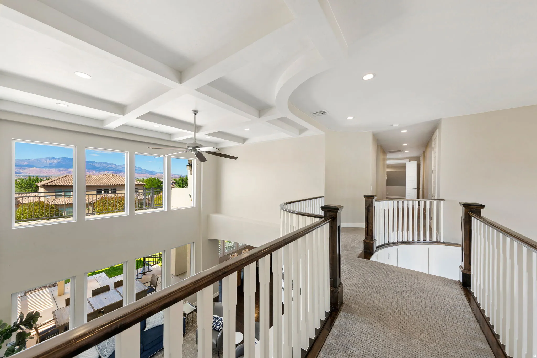 Upper-level hallway featuring a curved railing with dark wood and white balusters