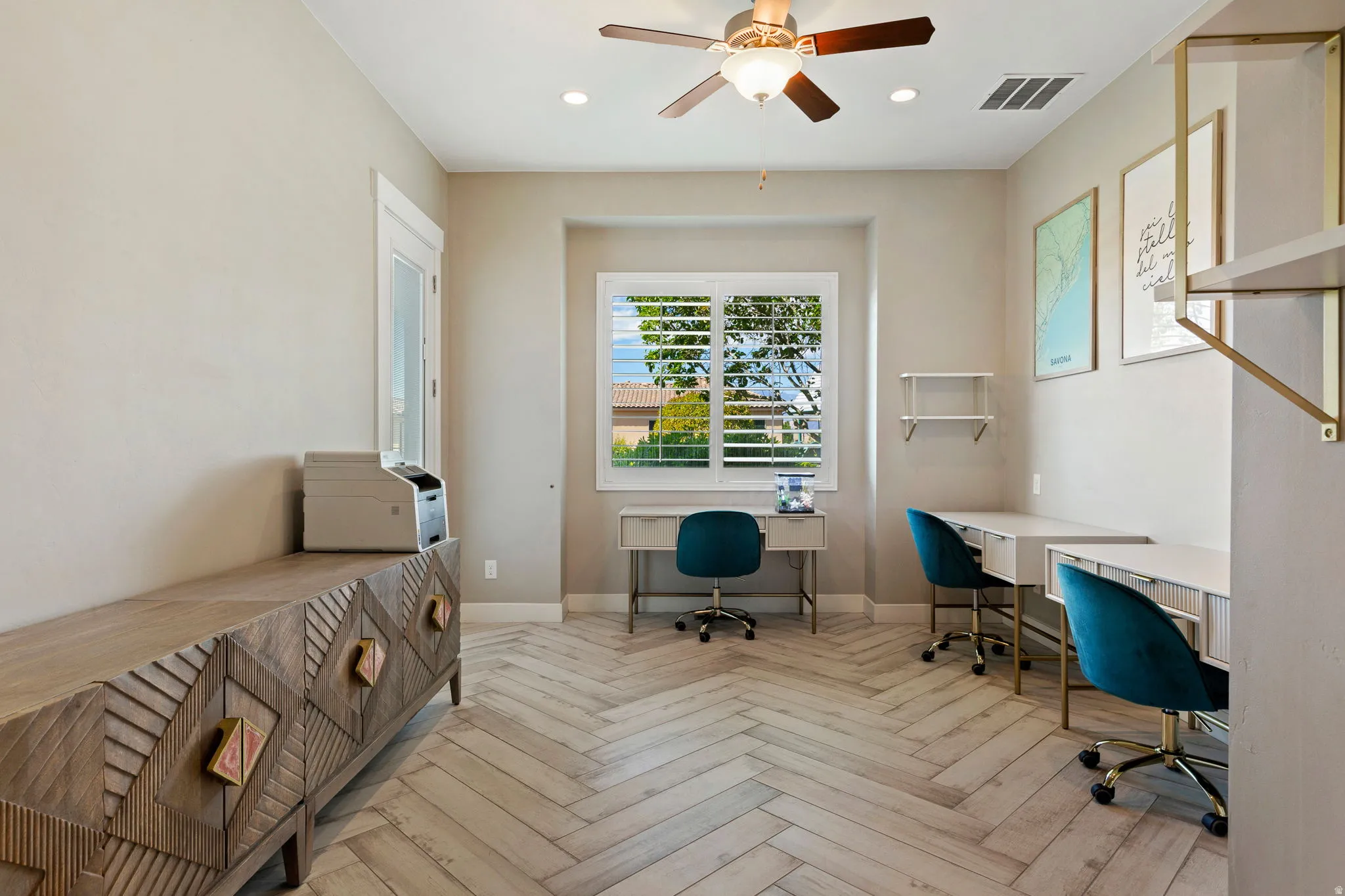 Herringbone wood-finish flooring complements this room featuring a window with plantation shutters, a ceiling fan with integrated lighting, and recessed lighting