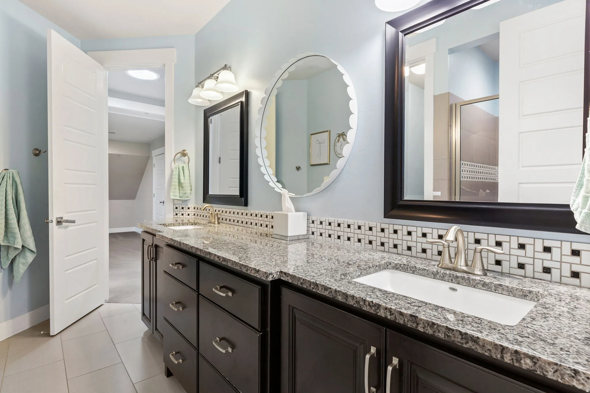 Dual vanity featuring dark wood-finish cabinetry, granite countertops, and undermount sinks