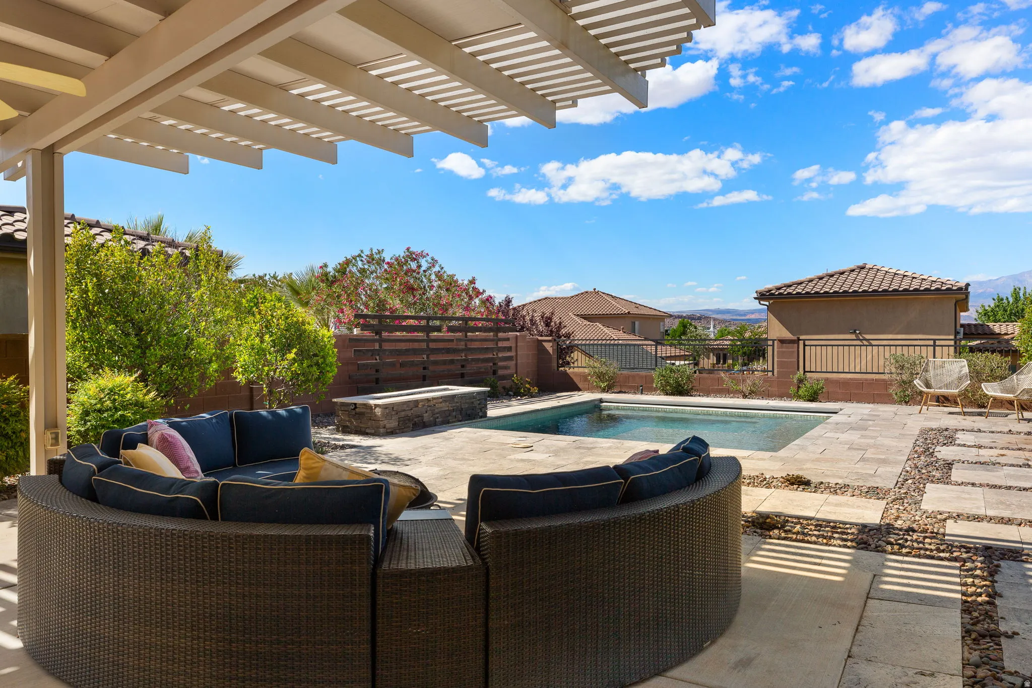 Expansive backyard featuring a pergola, swimming pool, stone fire pit, and paver patio