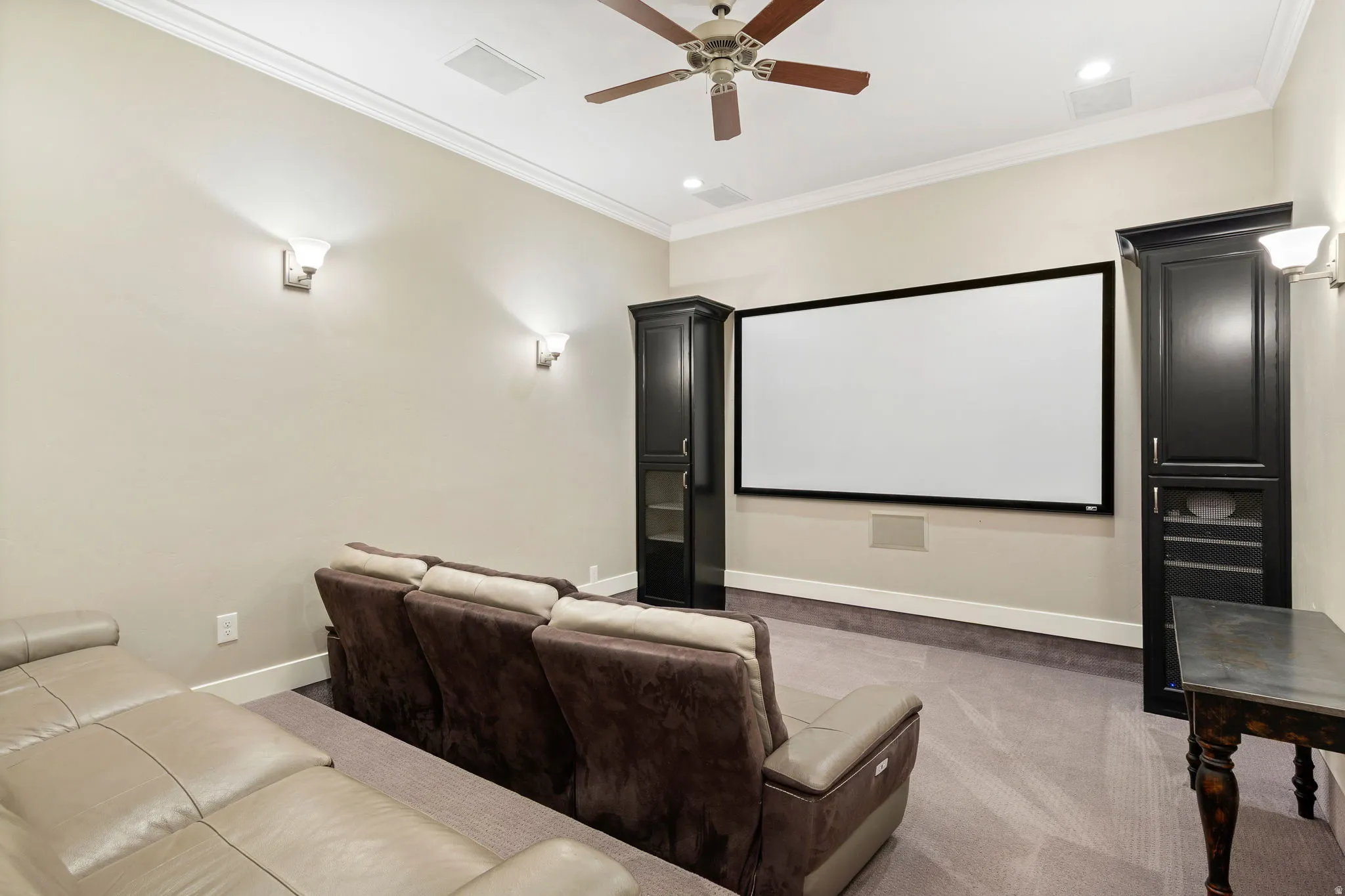 Dedicated media room featuring a large projection screen and built-in storage cabinetry
