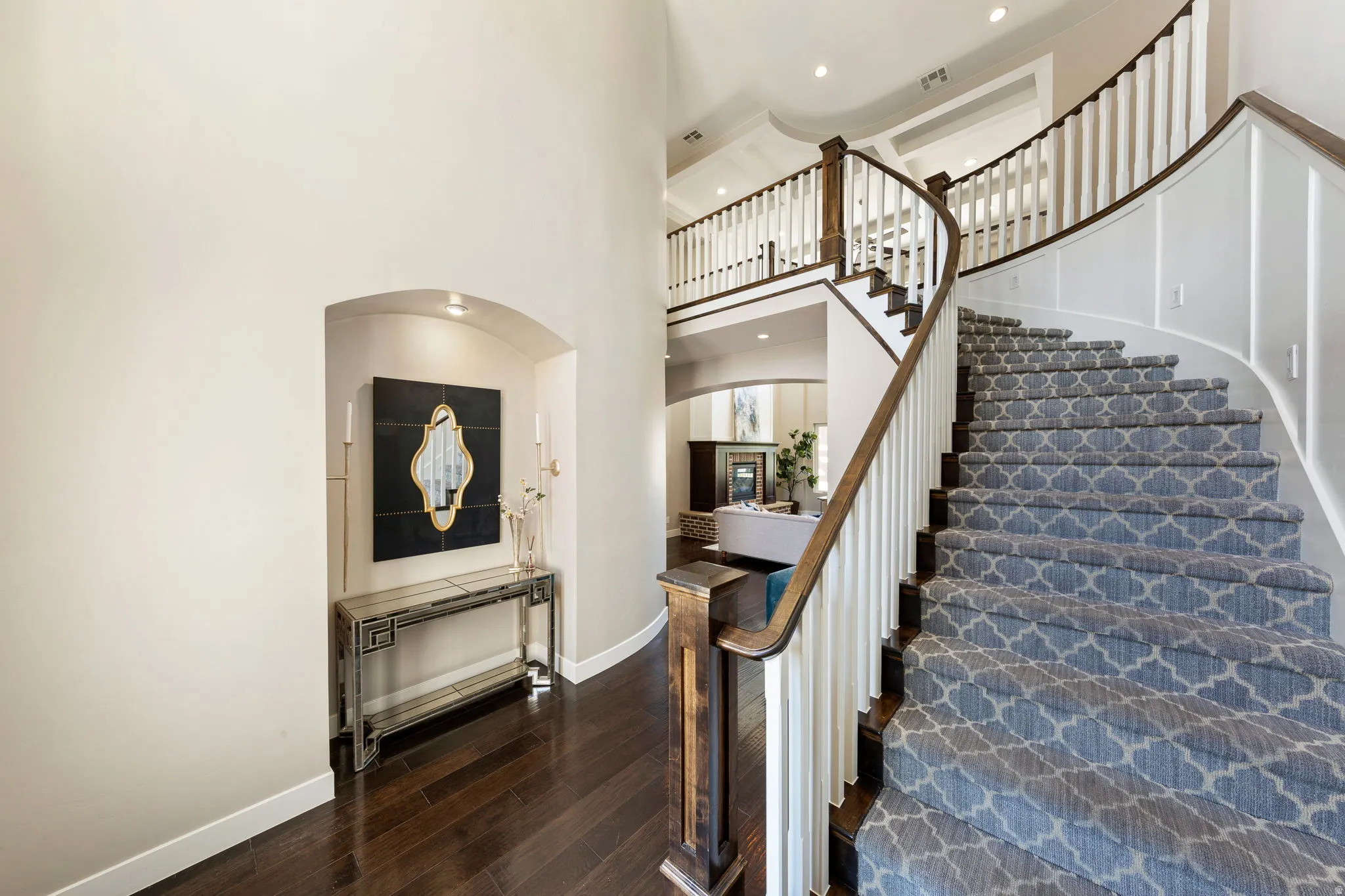 Grand curved staircase featuring patterned carpet treads, white risers, and dark wood handrails