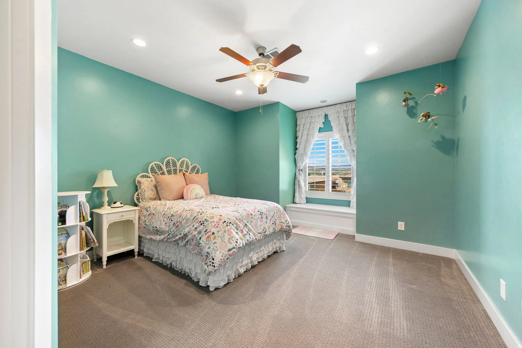 Carpeted room featuring a ceiling fan with light, recessed lighting, and a window with plantation shutters and a built-in window seat