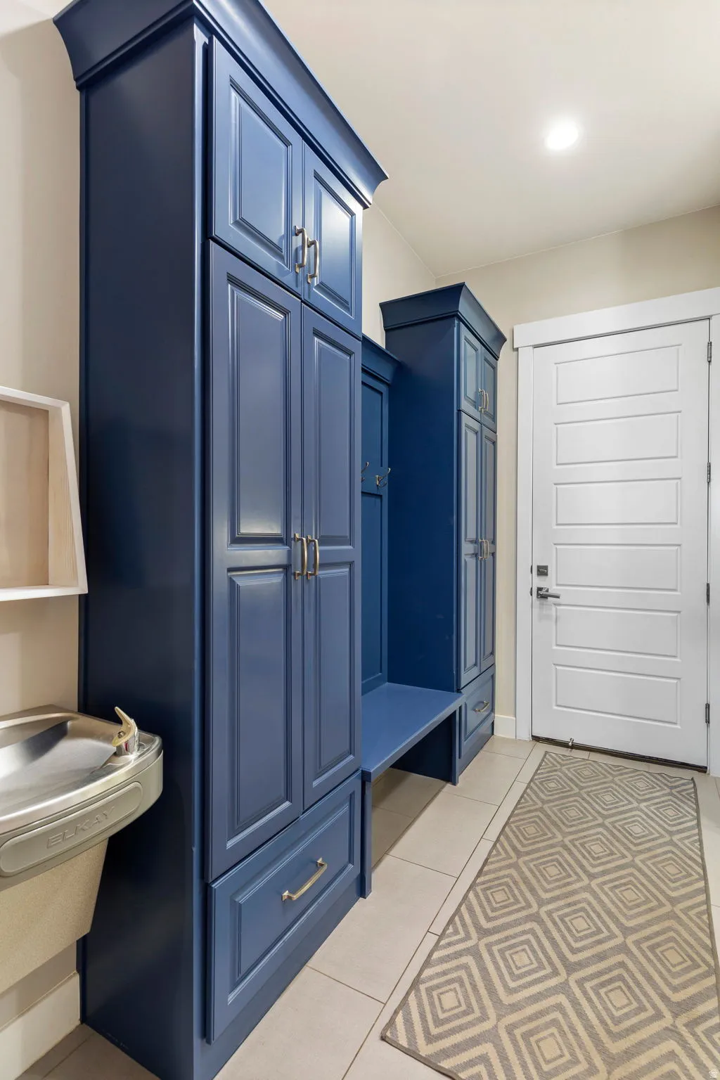 Built-in storage cabinetry in a deep blue finish, featuring shaker-style doors and drawers with brushed nickel hardware