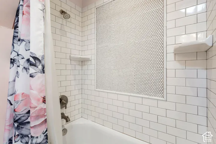 Bathtub with white subway tile surround, penny tile accent niche, and brushed nickel fixtures