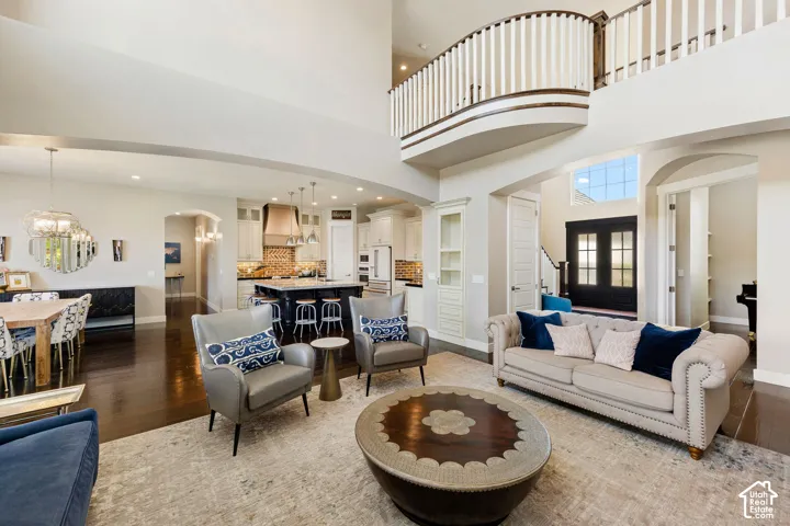 Open-concept living area with dark wood-finish flooring, a two-story ceiling, and an upper-level balcony